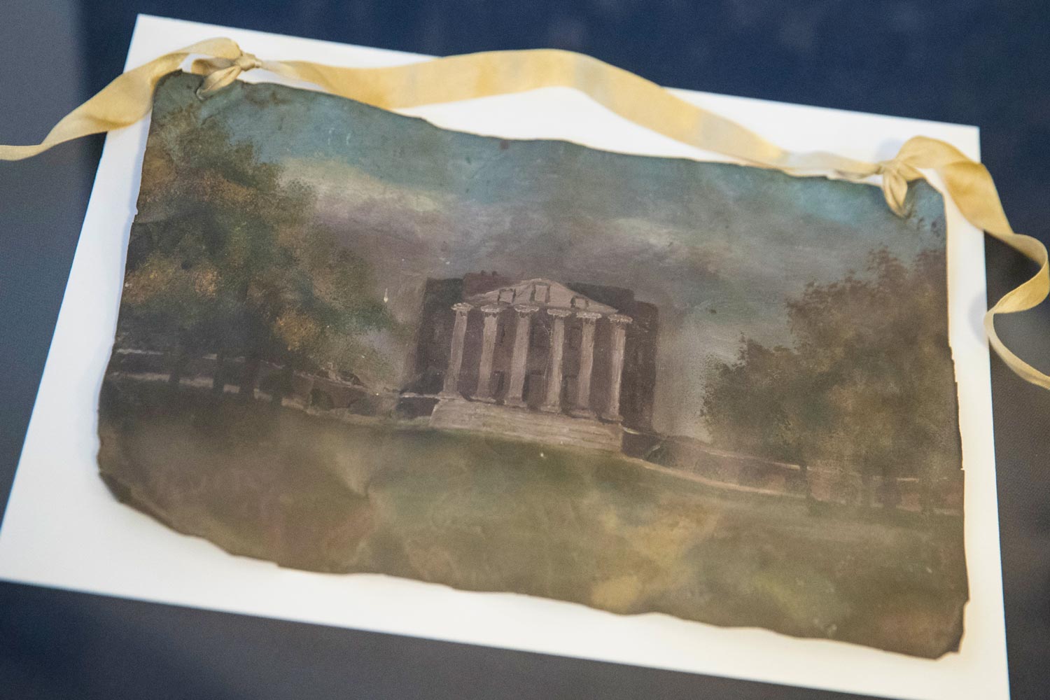 An image of the UVA Rotunda painted on a roof tile in a display case