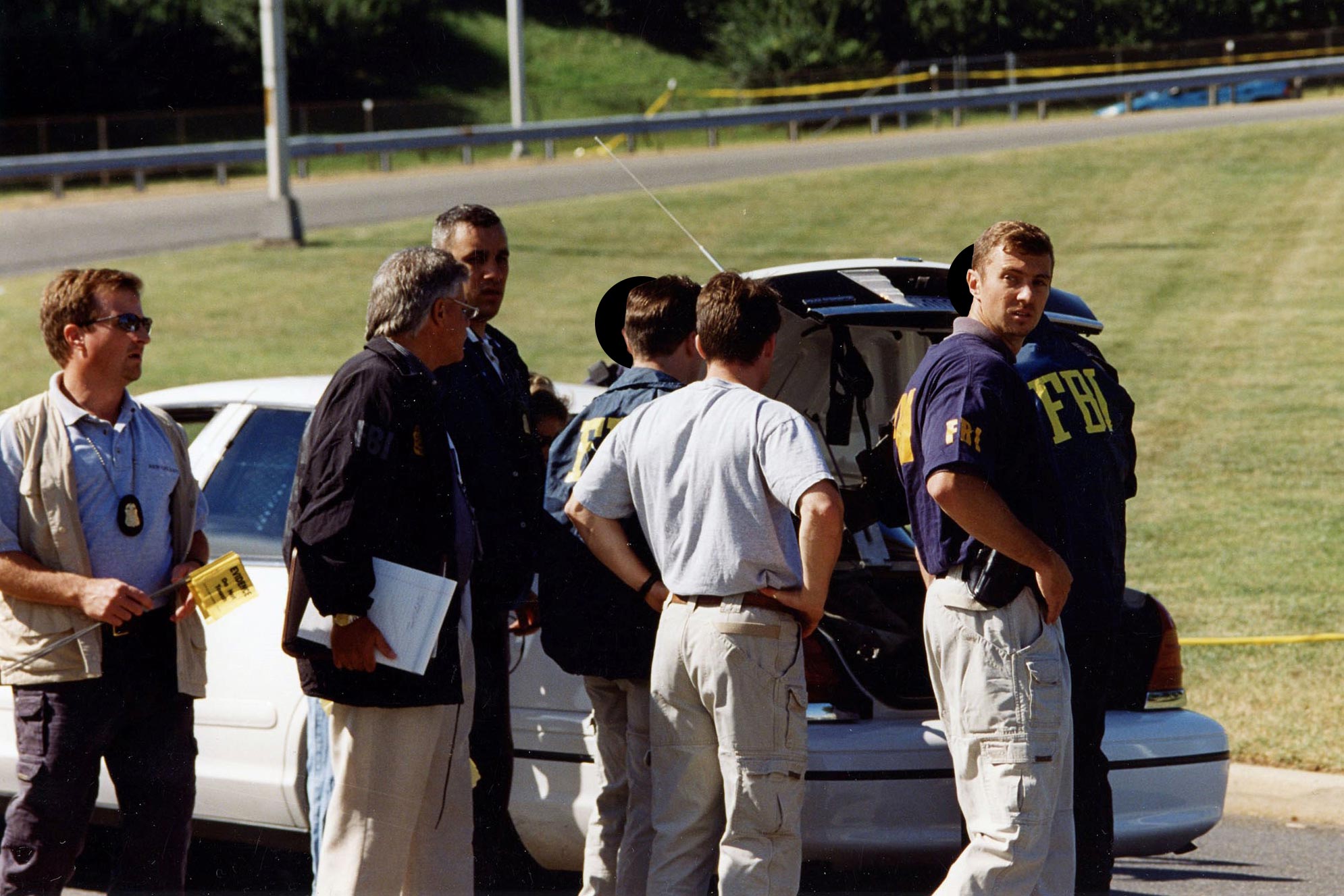 Group of FBI officers standing at the back of a car getting out equipment