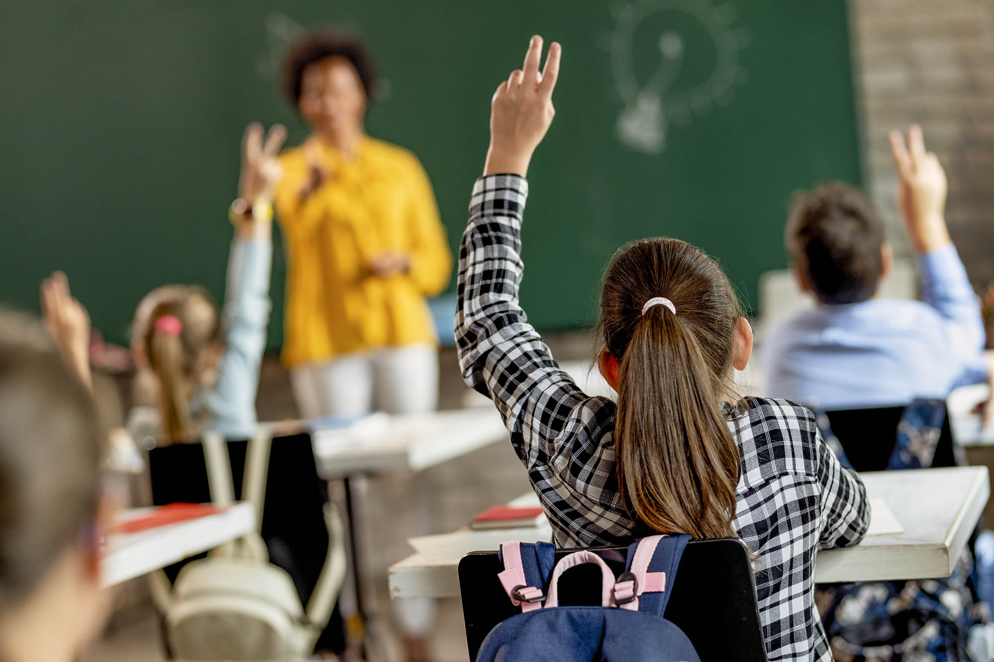 children raising their hands in class