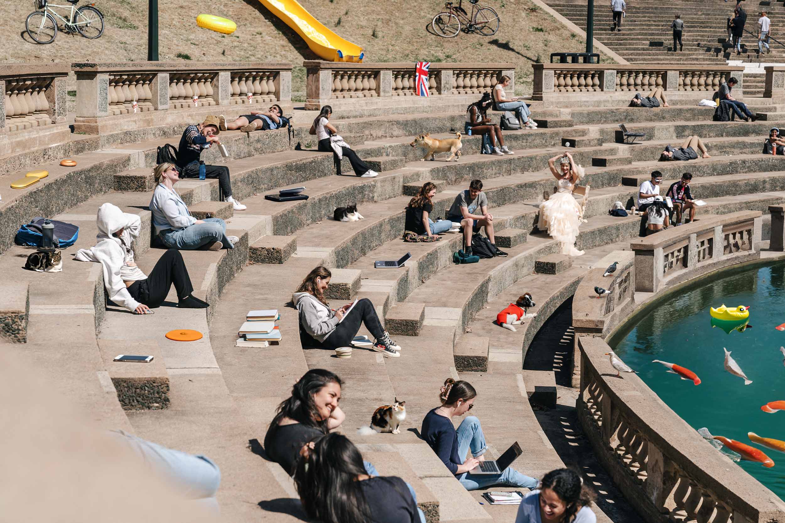 AI edited photo or students sitting in an outdoor amphitheater on a warm spring day on grounds with 25 changes