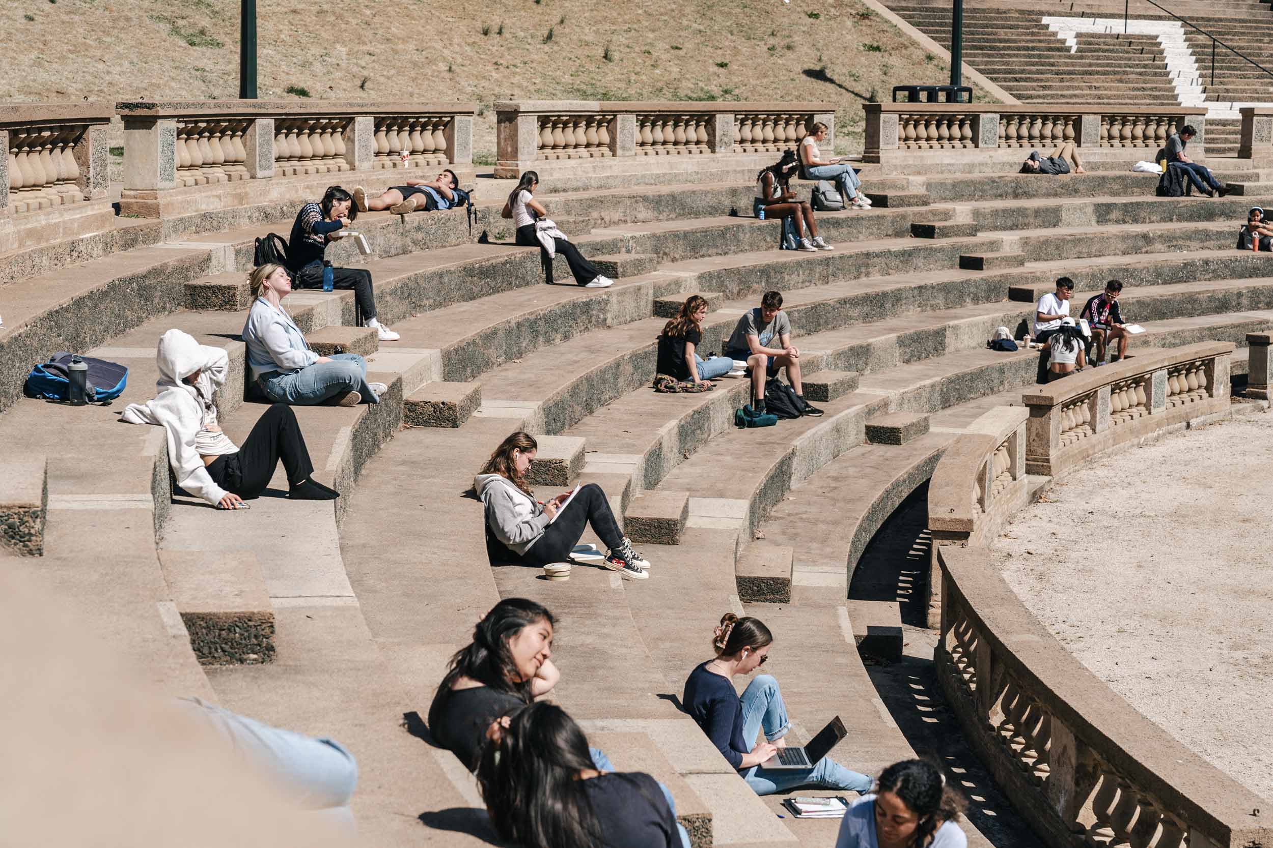 Originial photo of students sitting in an outdoor amphitheater on a warm spring day on grounds