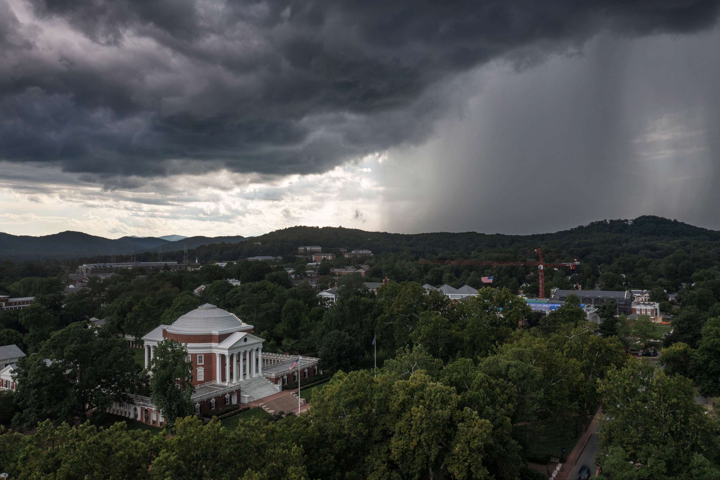 An aerial view of UVA Grounds with dark clouds. On the left is the rotunda, on the right is a wall of rain.