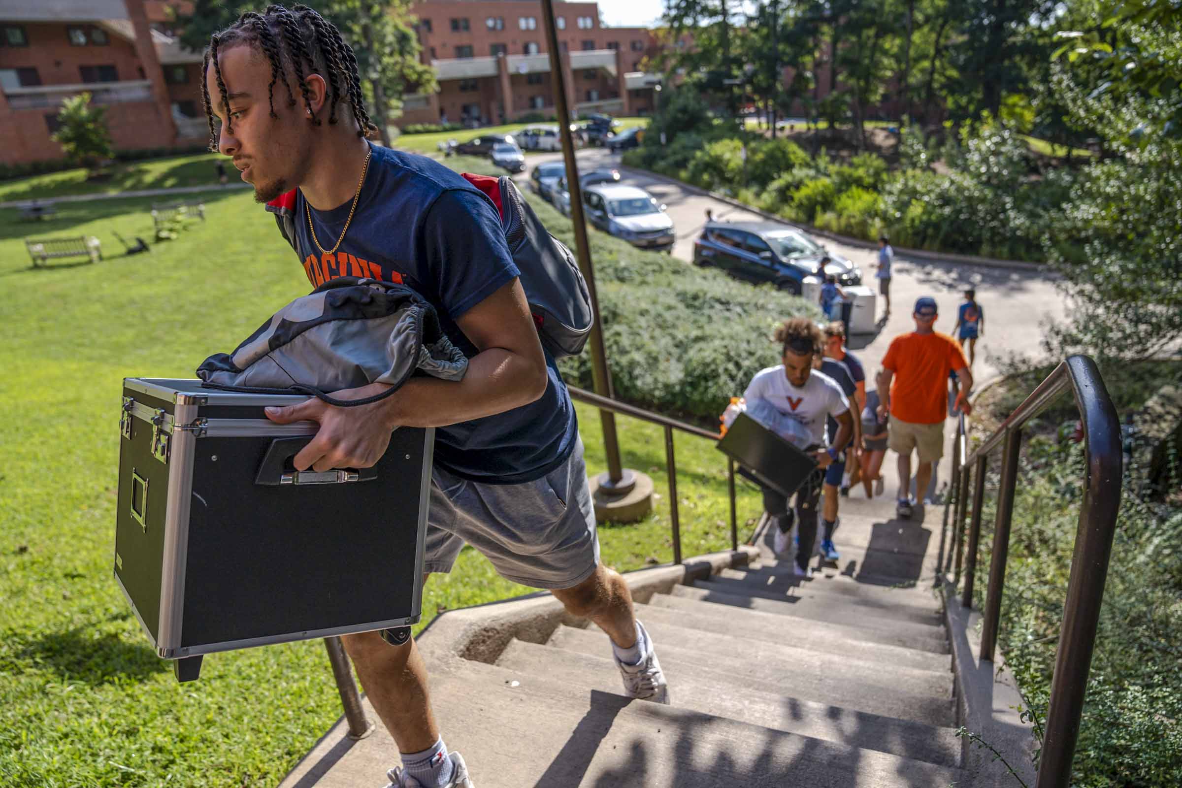 College students in Virginia shirts climb a flight of stairs while holding boxes