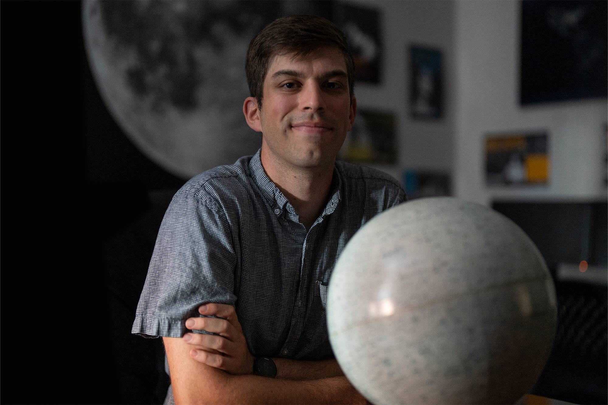 Dark portrait of Matt Pryal with a globe placed in front of him