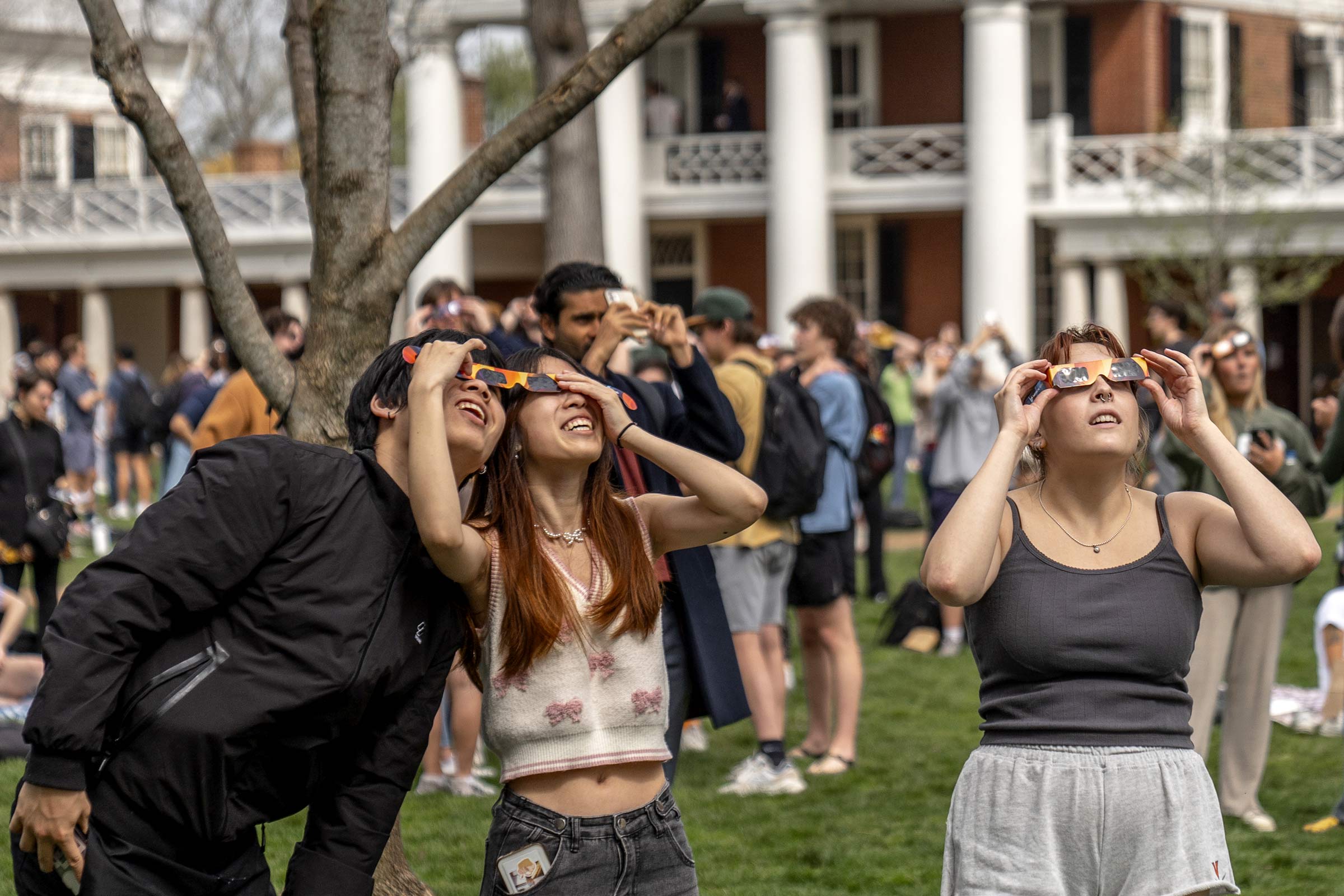Two students share a pair of glasses and look through a side each at the same time