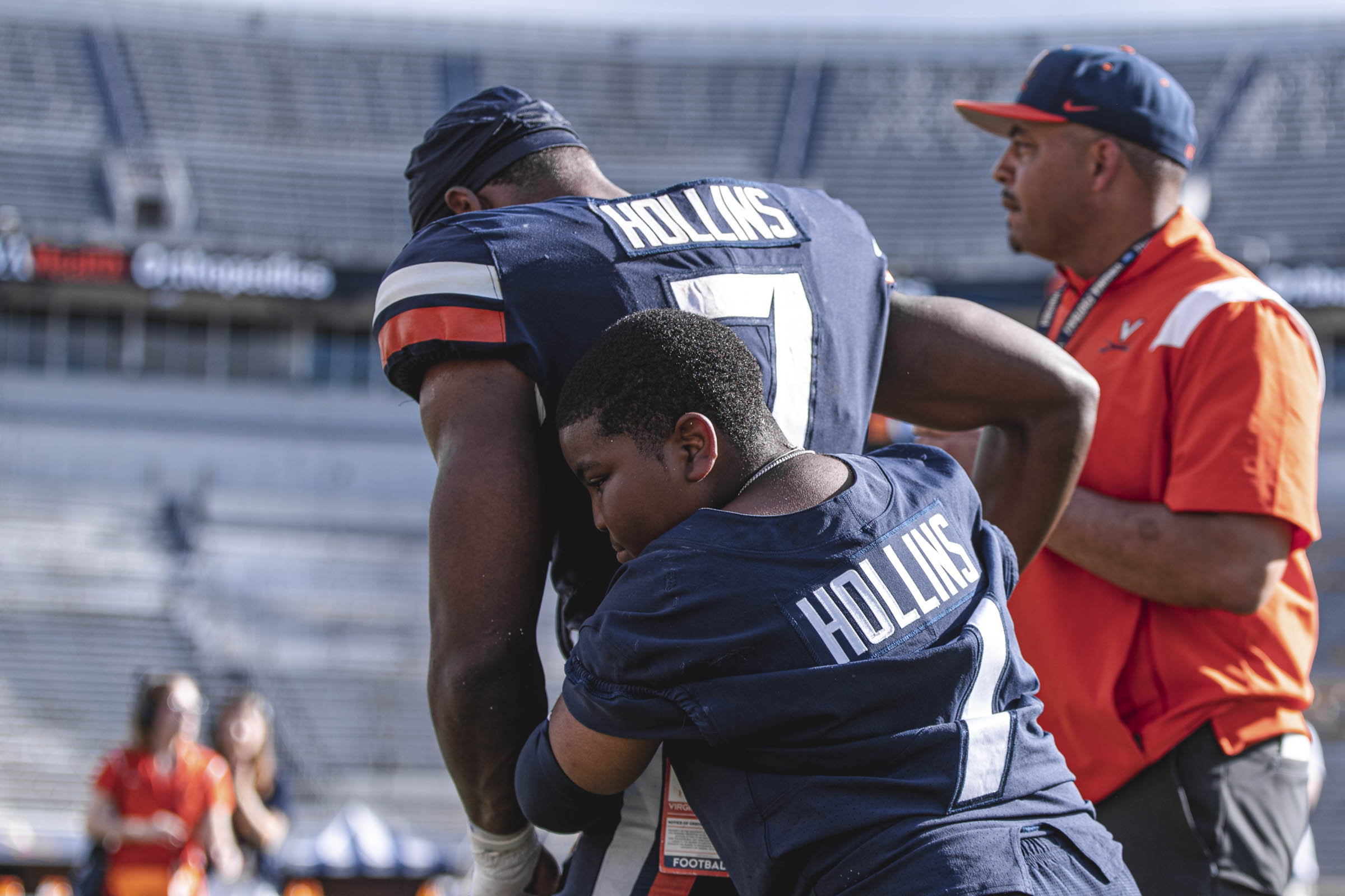 Candid of Mike Hollins on the football field being hugged by his little brother Deuce