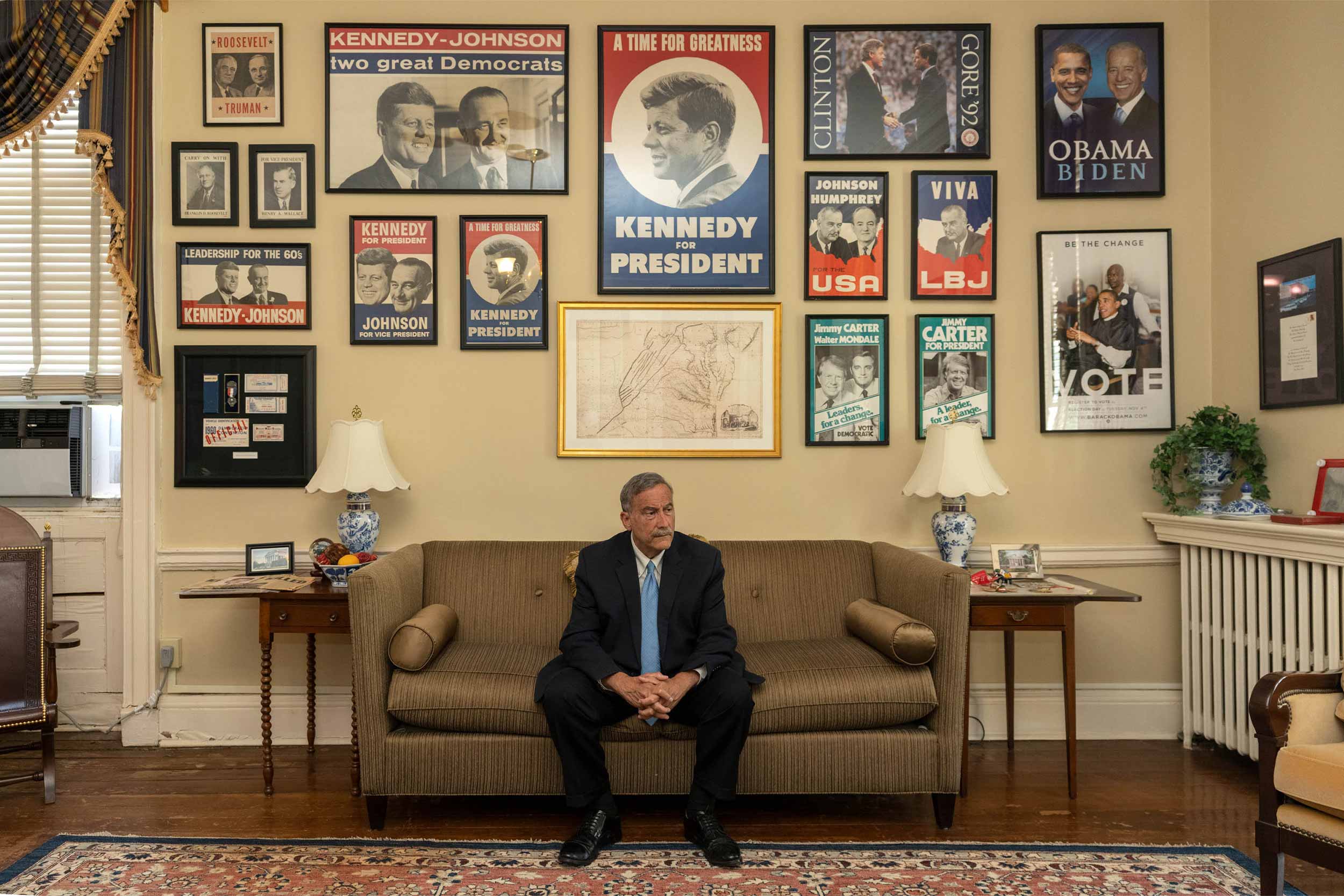 Larry Sabato sitting on a couch under a bunch of political signage