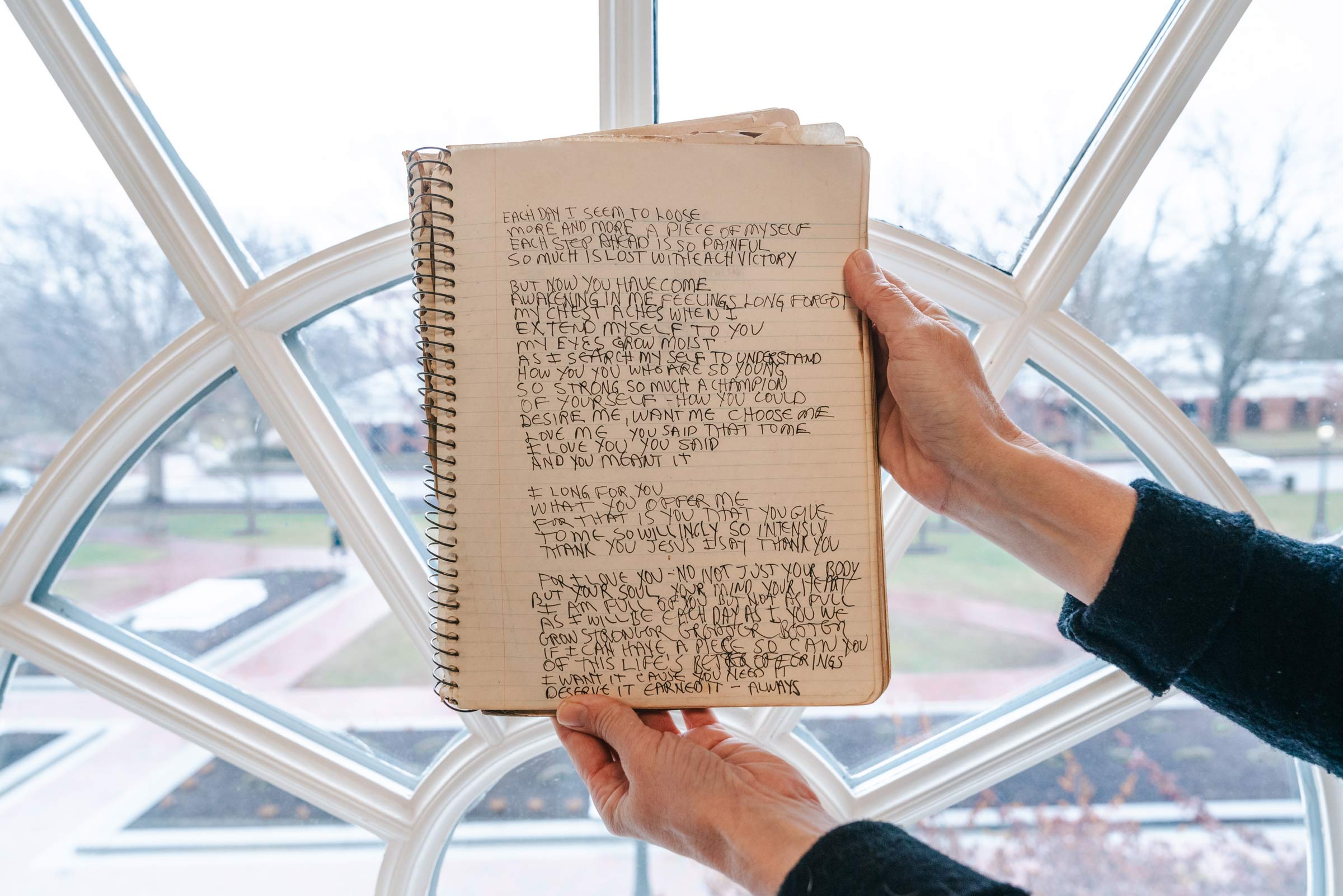 A journal is held up in front of a half circle window