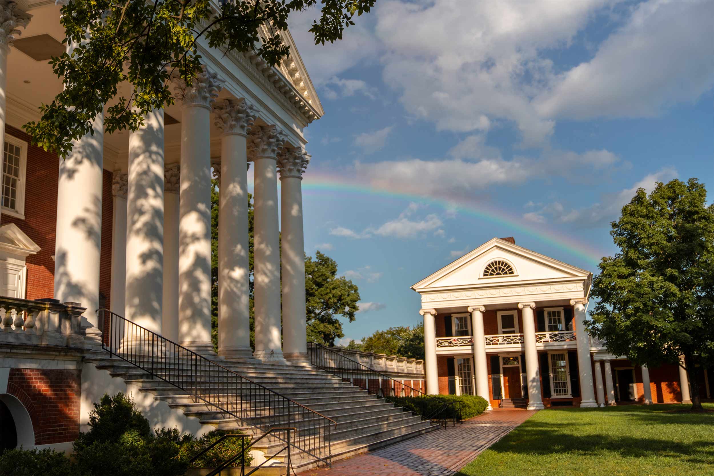 Low angle photo of a rainbow in the sky after a storm. The rotunda stands on the left and a pavilion is situated on the lower right. 