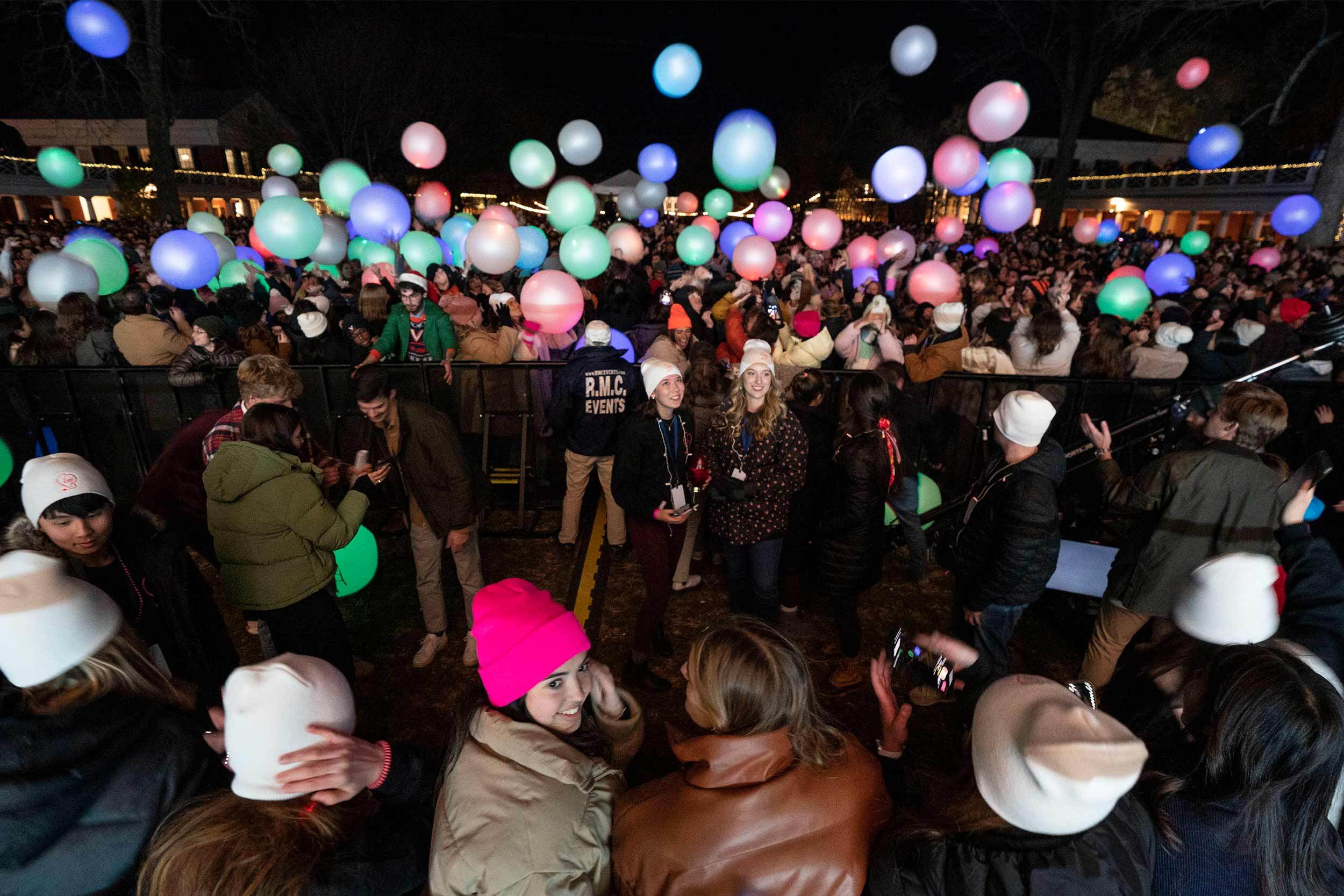 Students toss colored glowing balls in the air on the Lawn