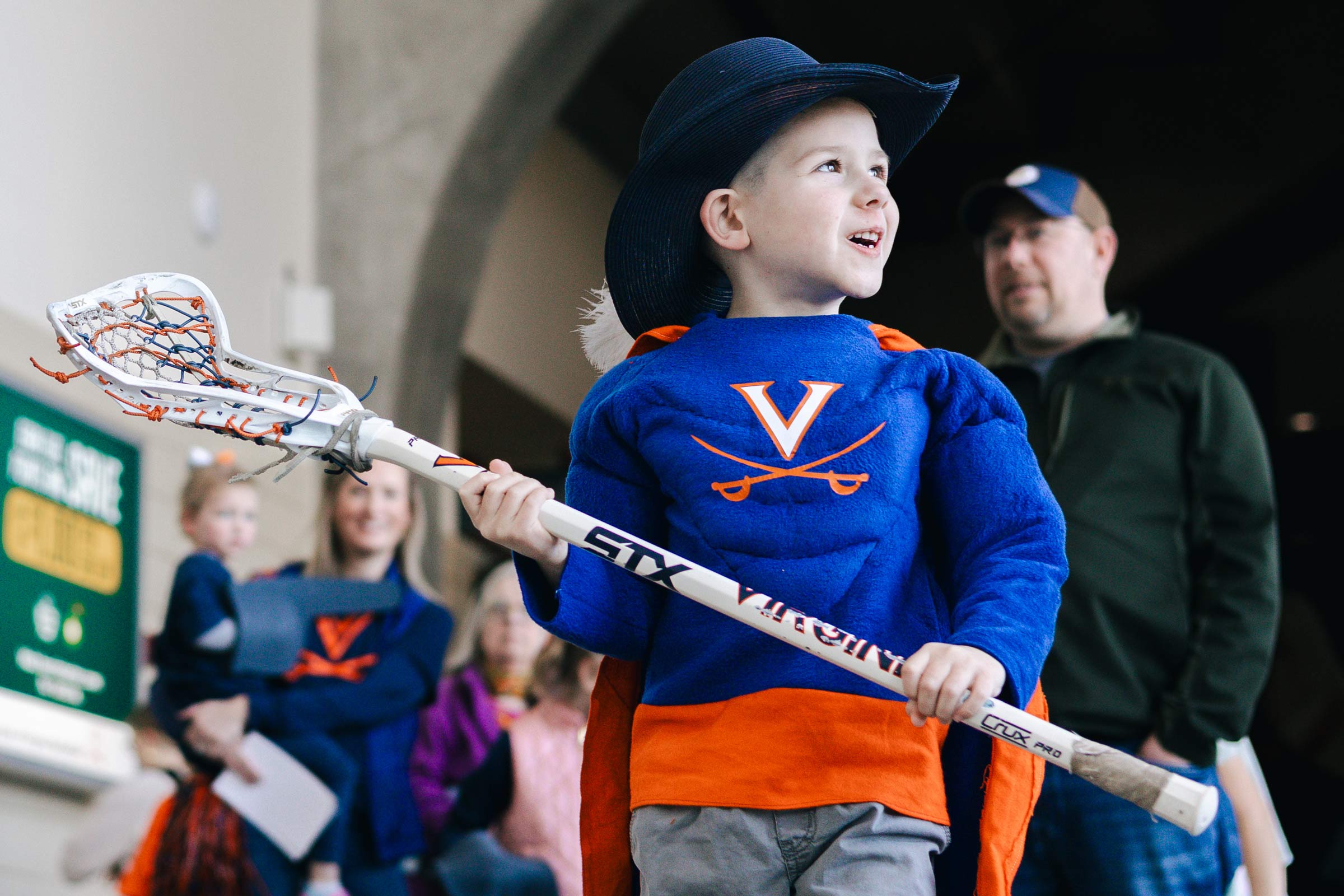 A little boy dressed as Cavman cradles a lacrosse stick