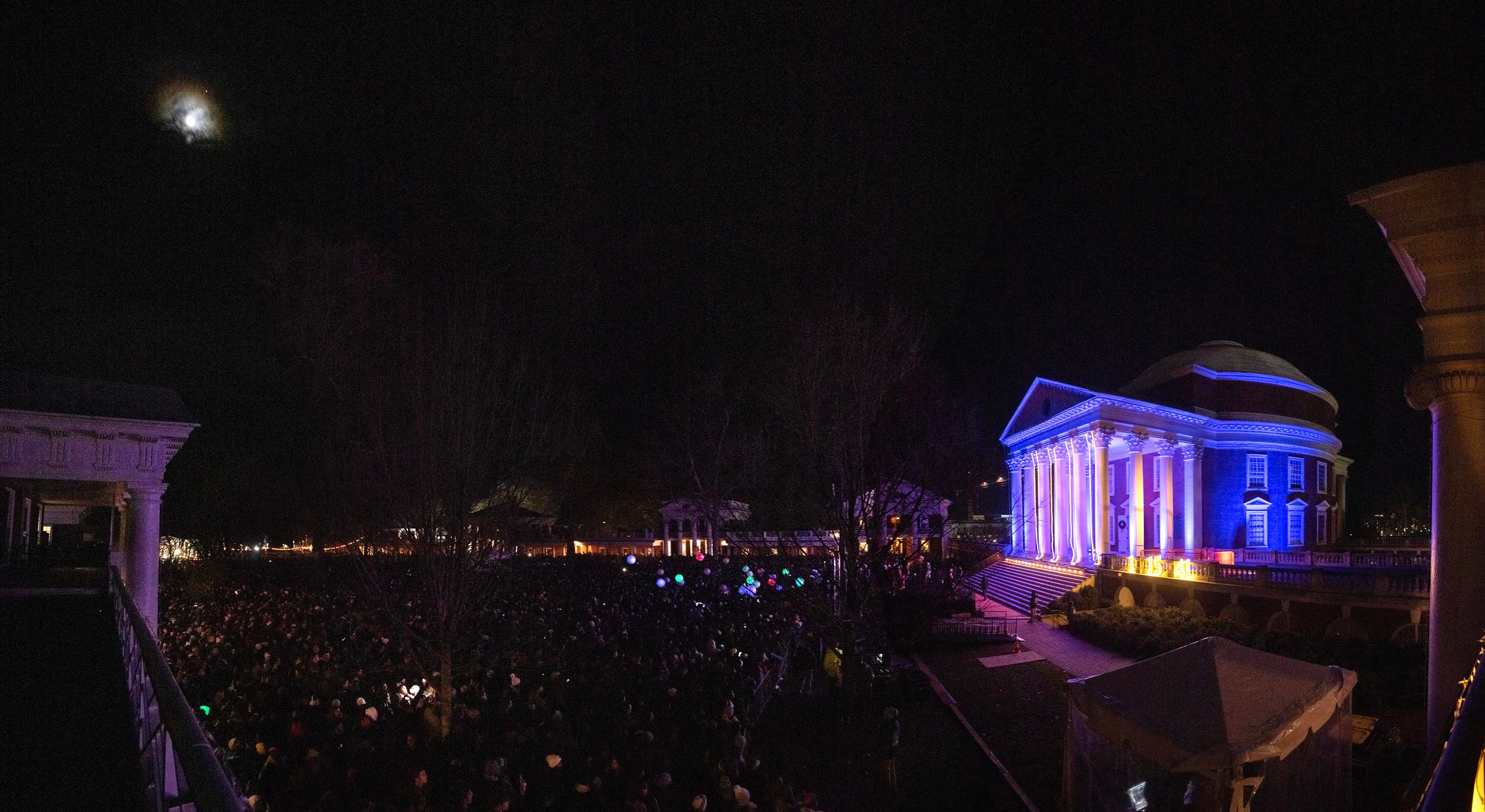 The Rotunda in purple lights while a crowd watches