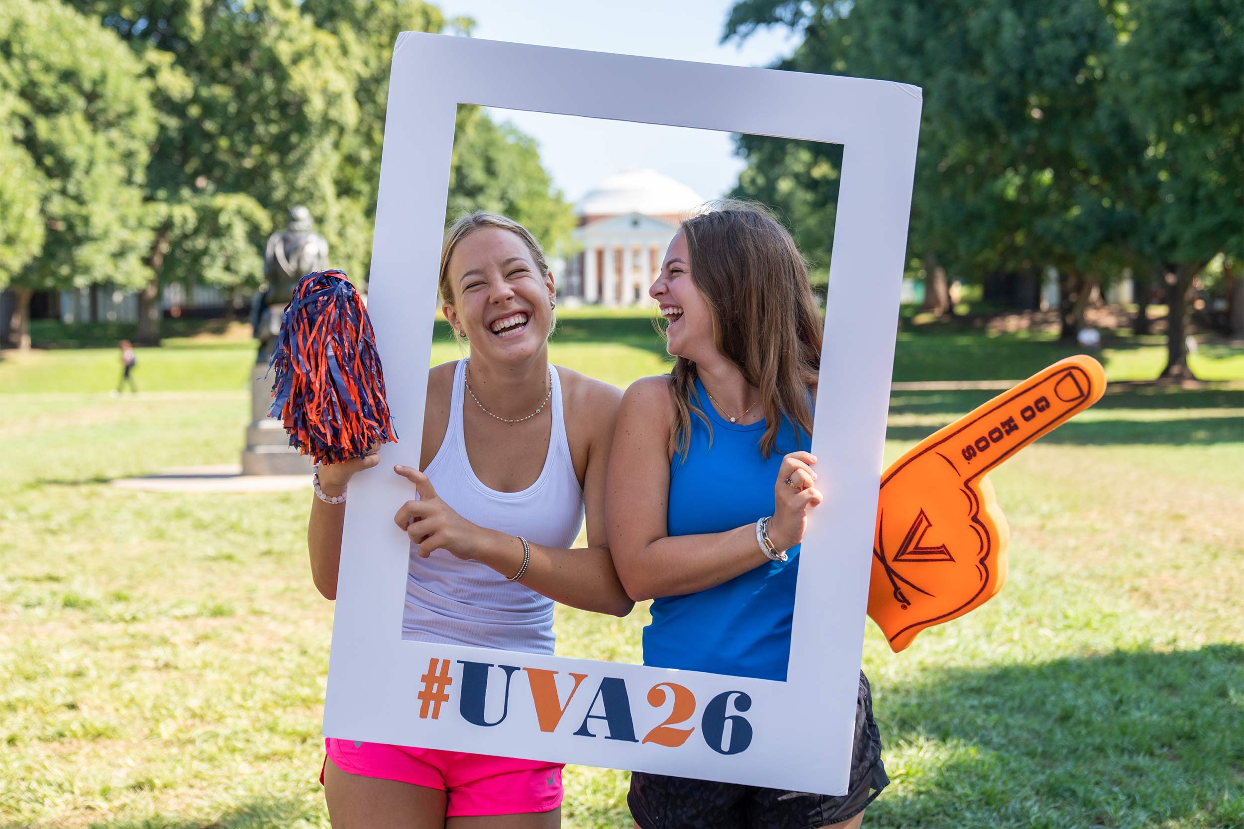 Two students holding the #UVA26 frame laugh together