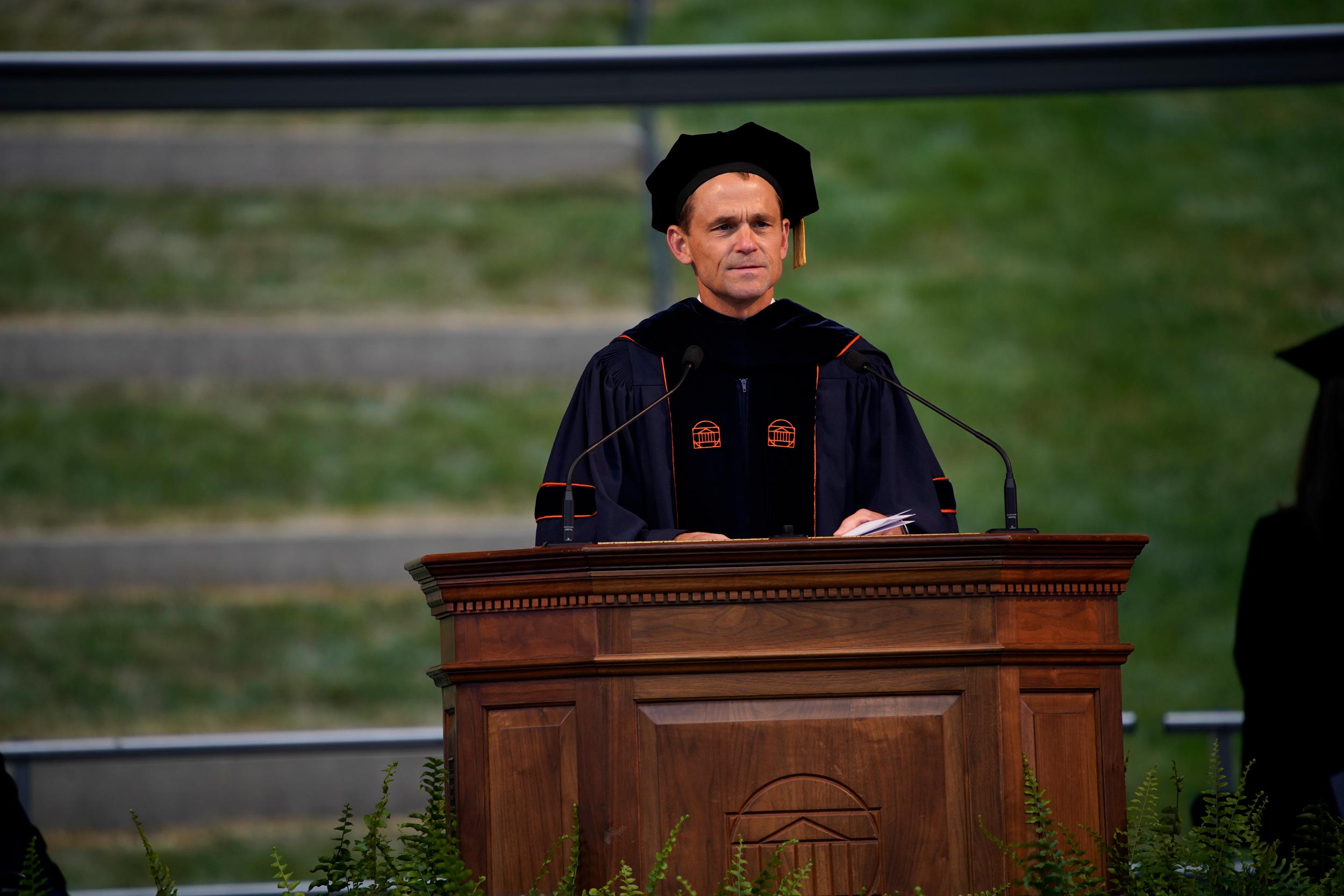 President Ryan standing at a wooden podium giving a speech at graduation