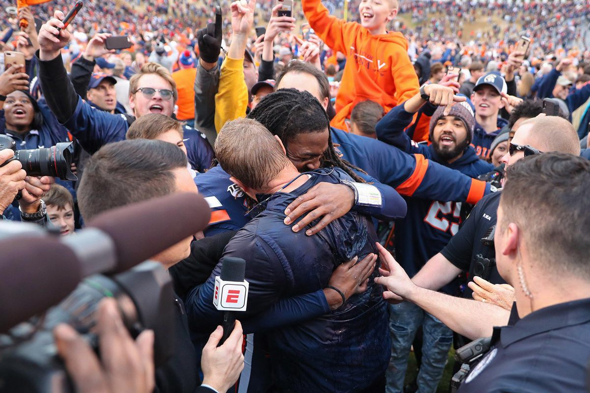 Mendenhall and UVA quarterback Bryce Perkins hug with fans surrounding them