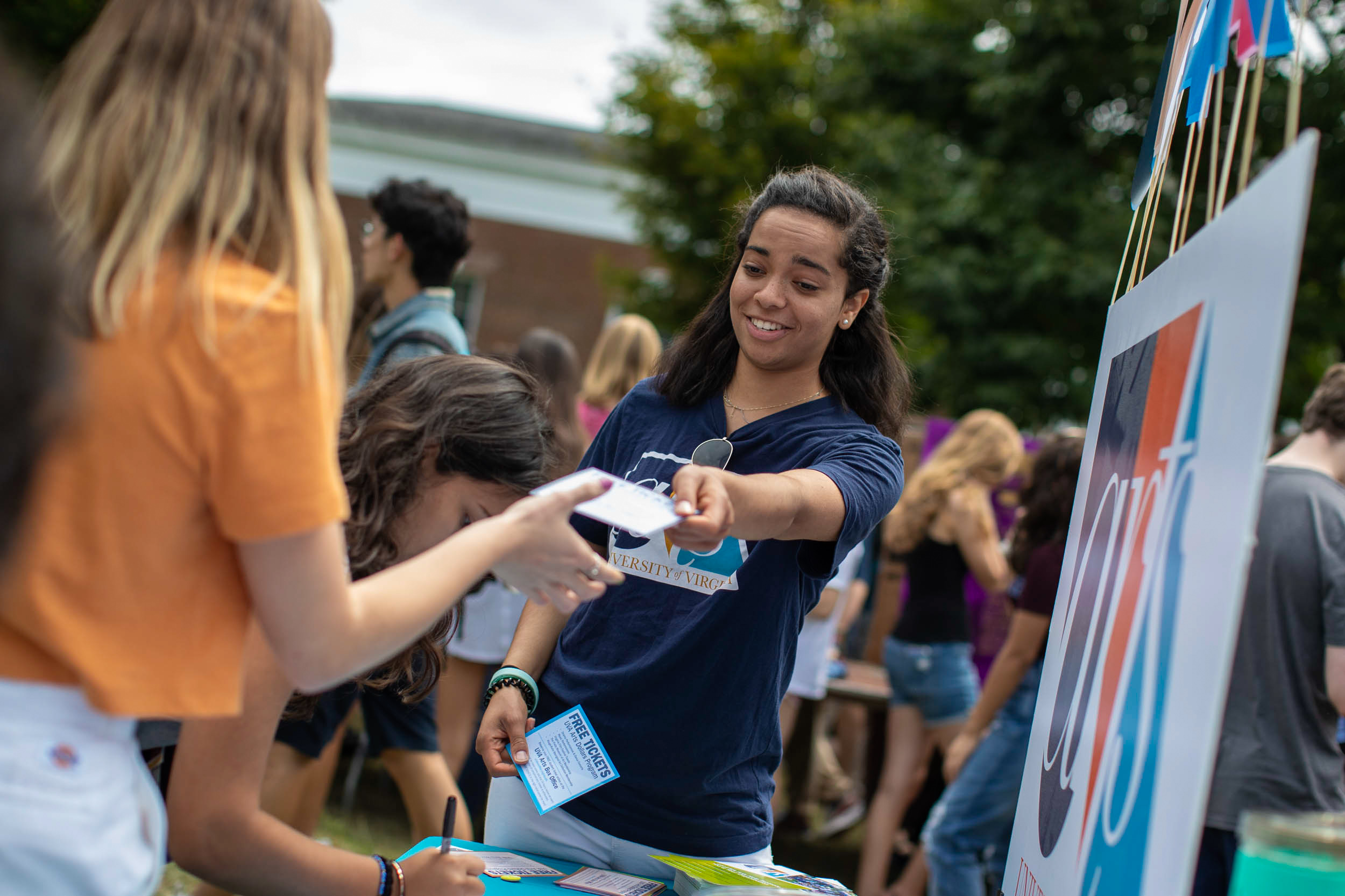 Student handing out a coupon while students fill out cards at their booth