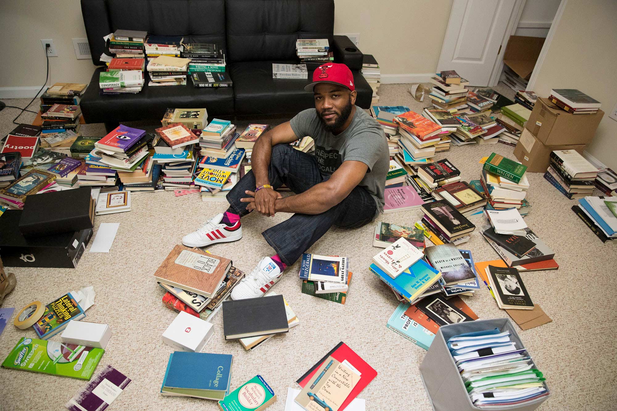 Carson sits on his homes floor surrounded by books