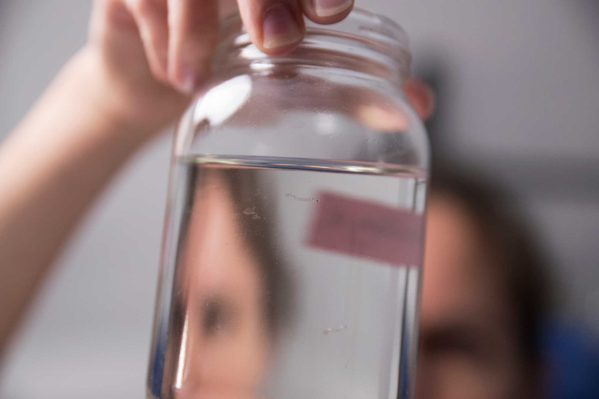 Person holding a mason jar full of water