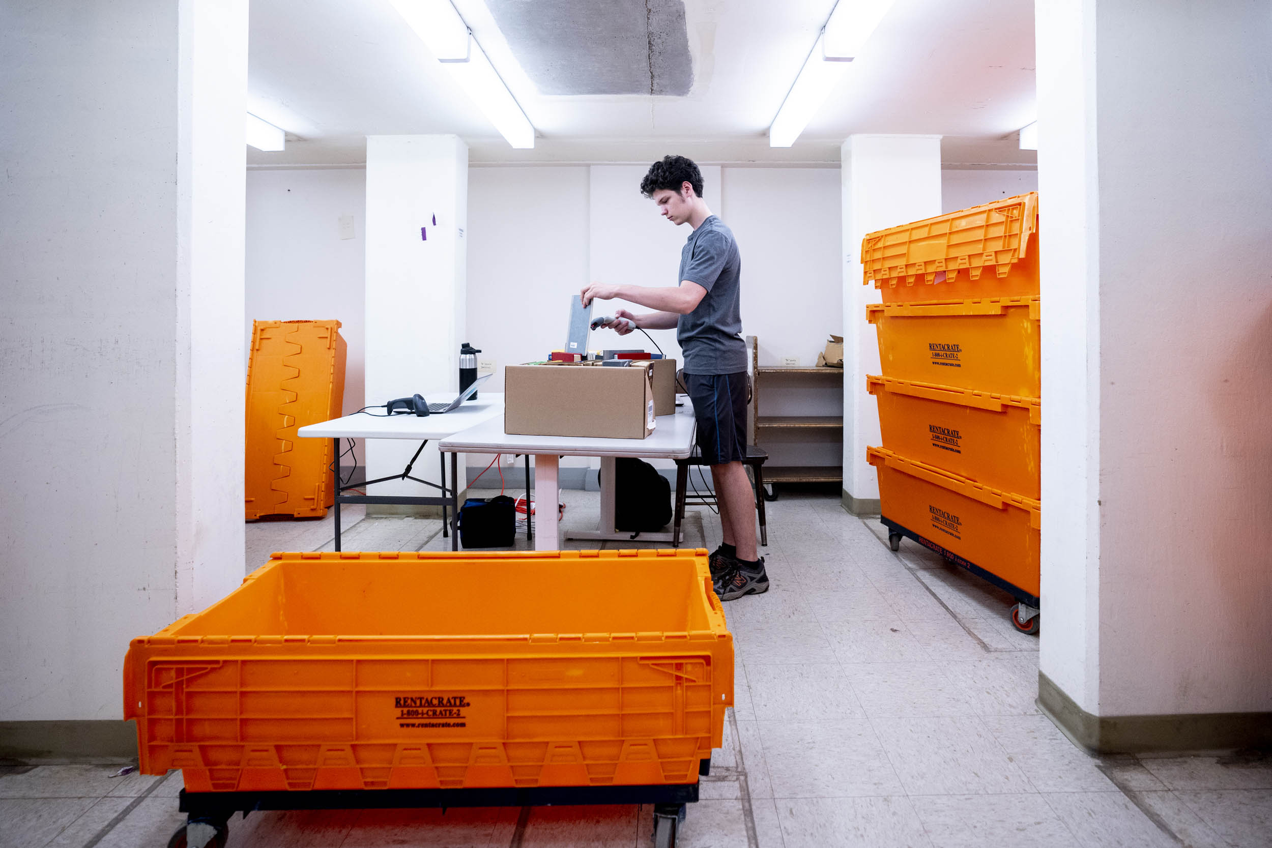 Jackson D’Errico scans books to place in bright orange tubs