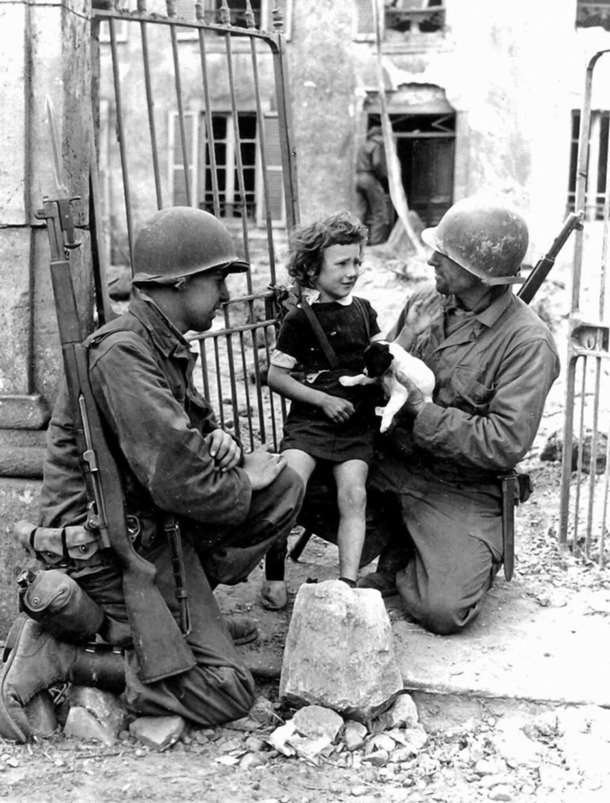 Black and white image of two soldiers holding a little girl and puppy.