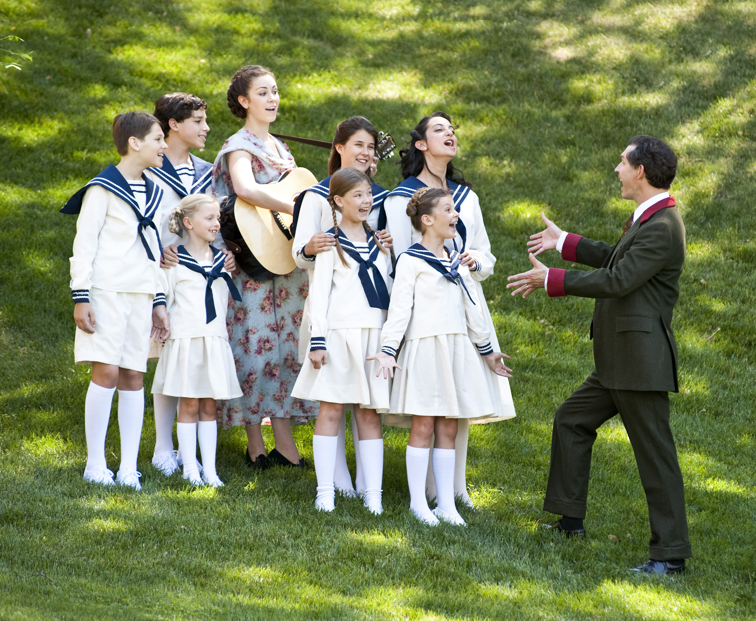 Actors on a green hill as they play sing during a rehearsal for the sound of music