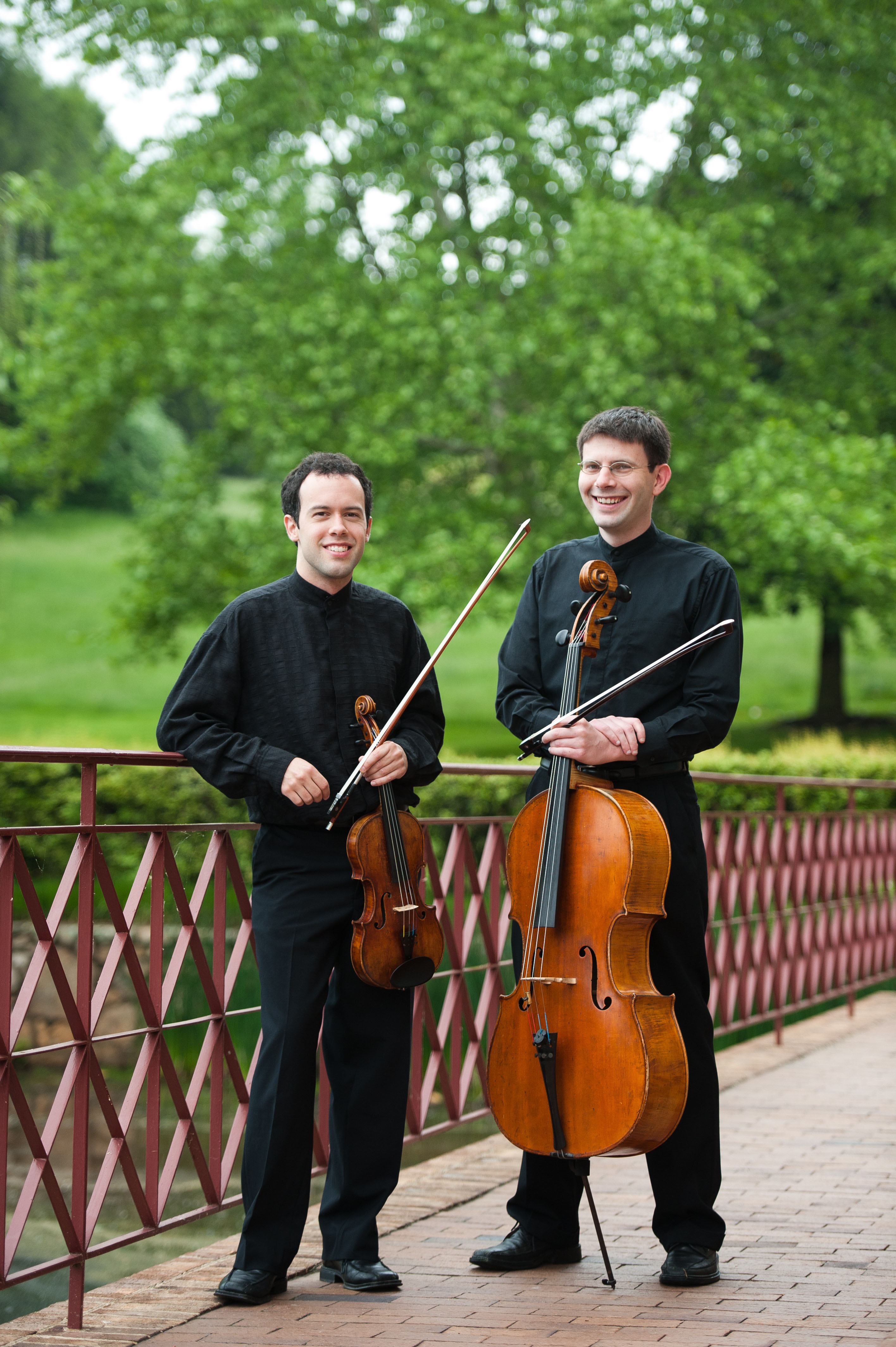 David Colwell, left, and Adam Carter, right stand with their musical instruments and smile at the camera