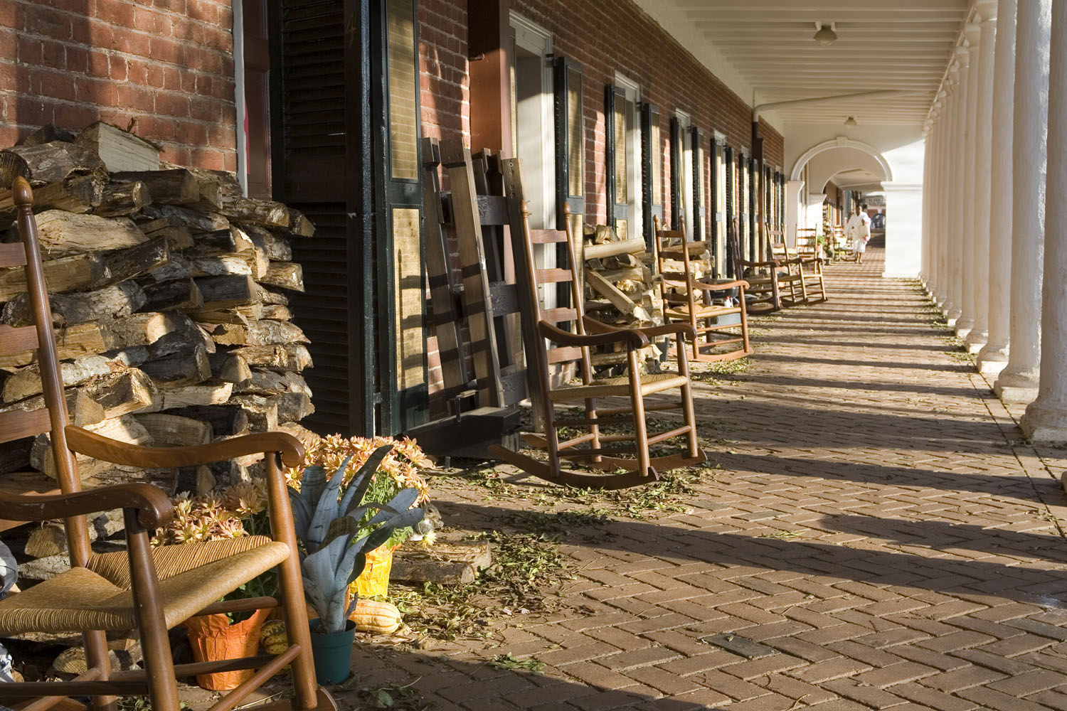 brick Sidewalk with rocking chairs and firewood outside of the rooms on the lawn