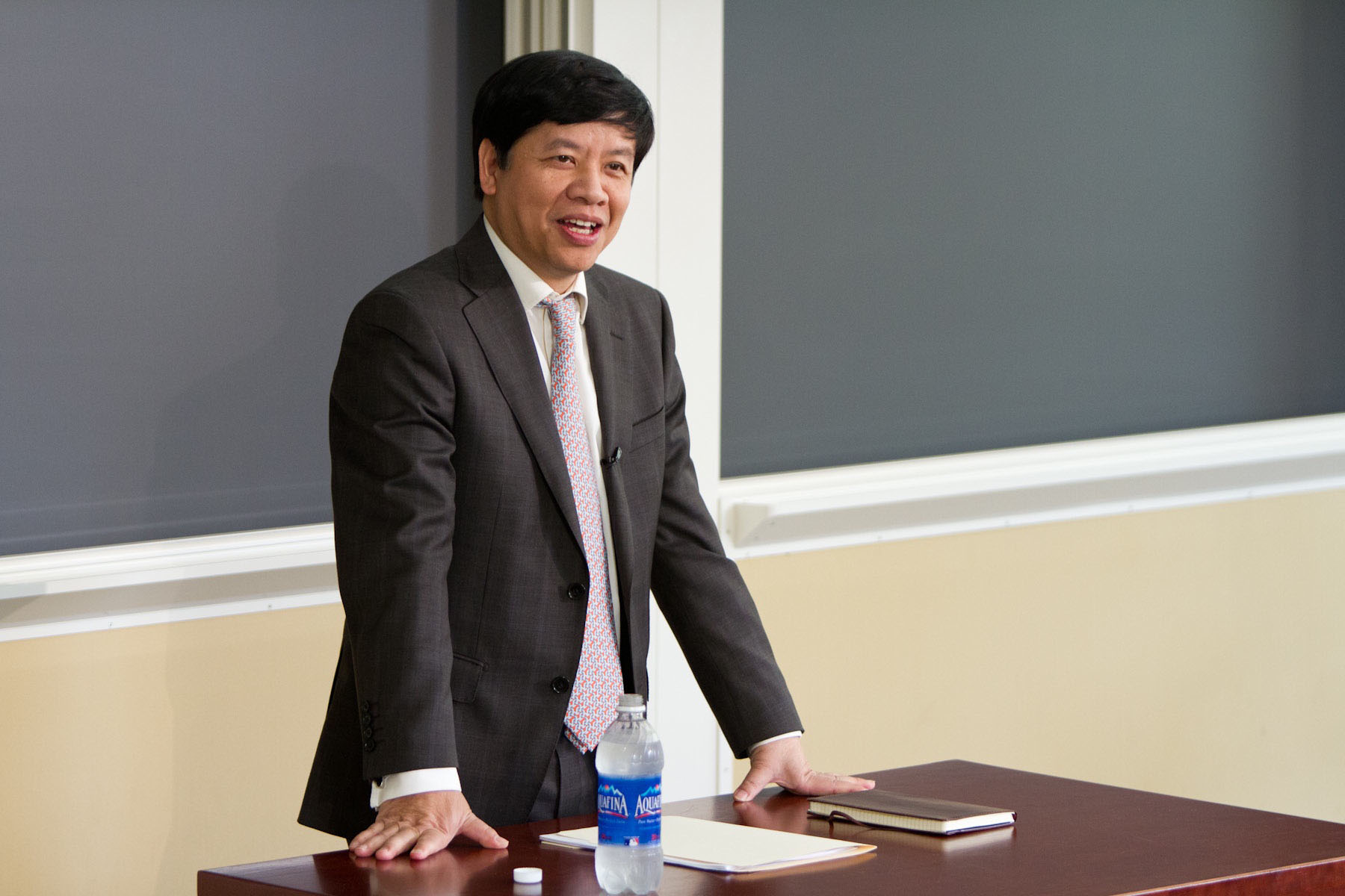 Nguyen Quoc Cuong speaking to a class from a desk