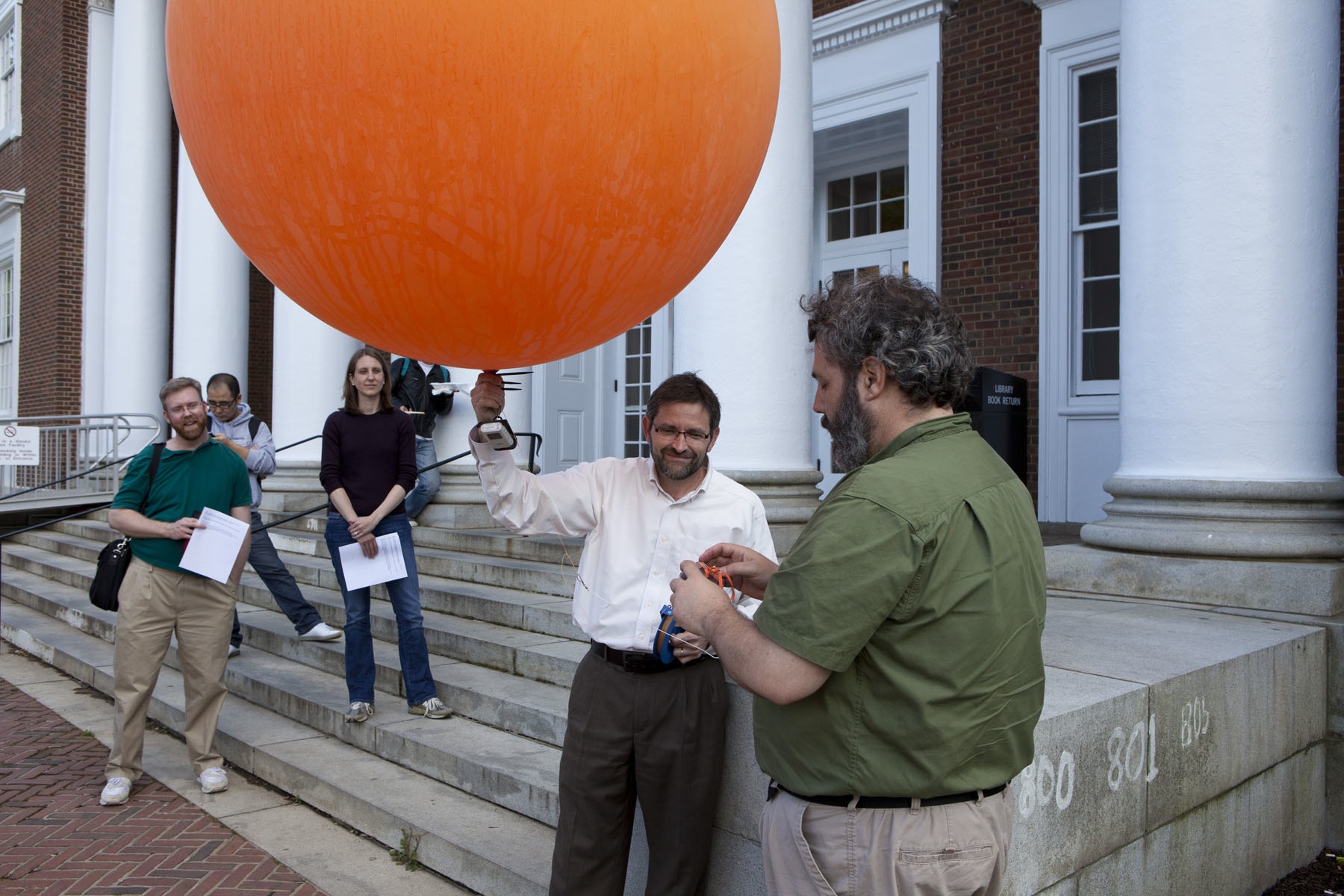 Man holding a giant orange balloon