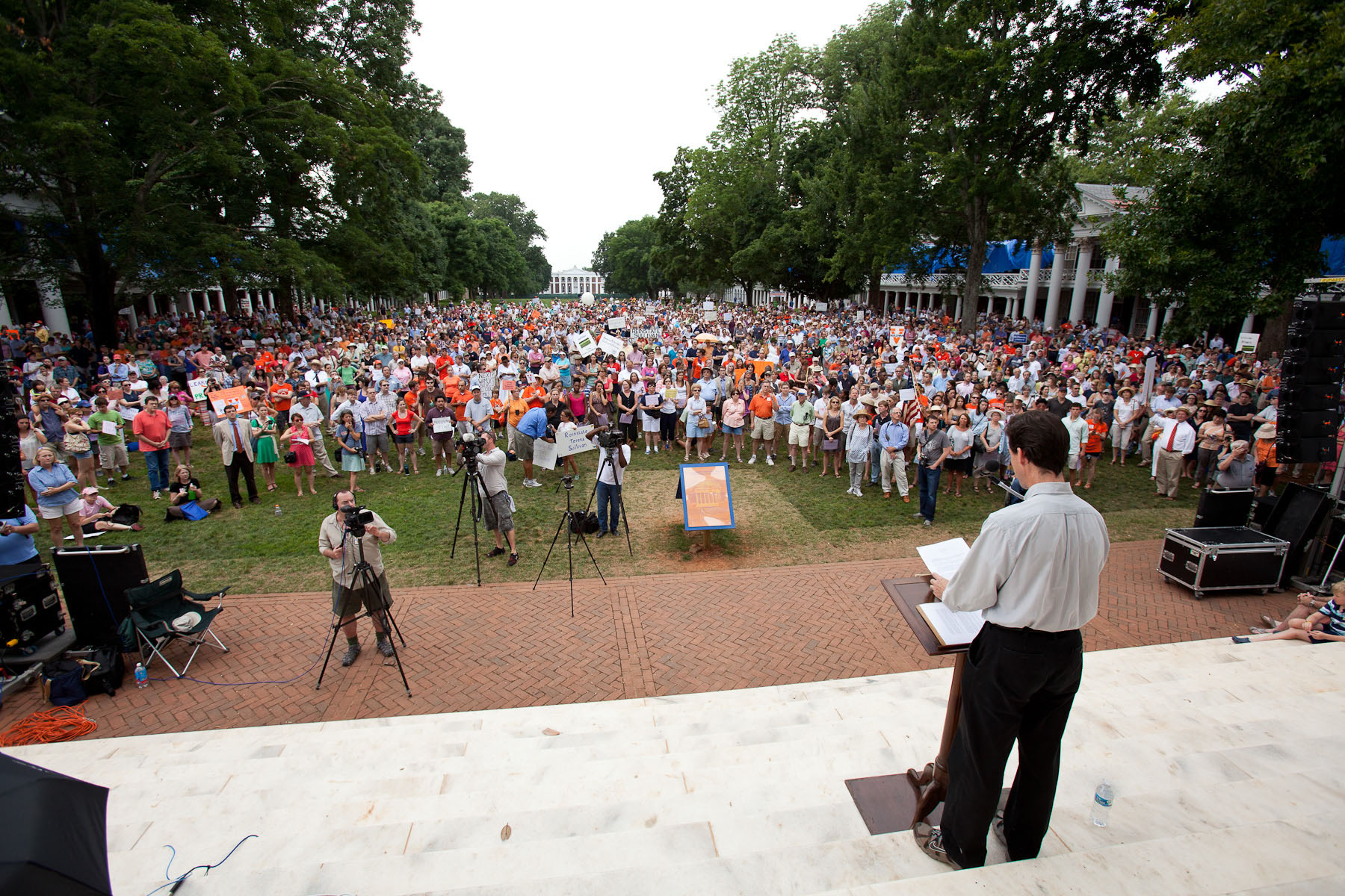 Man stands at a podium giving a speech to a Lawn full of people