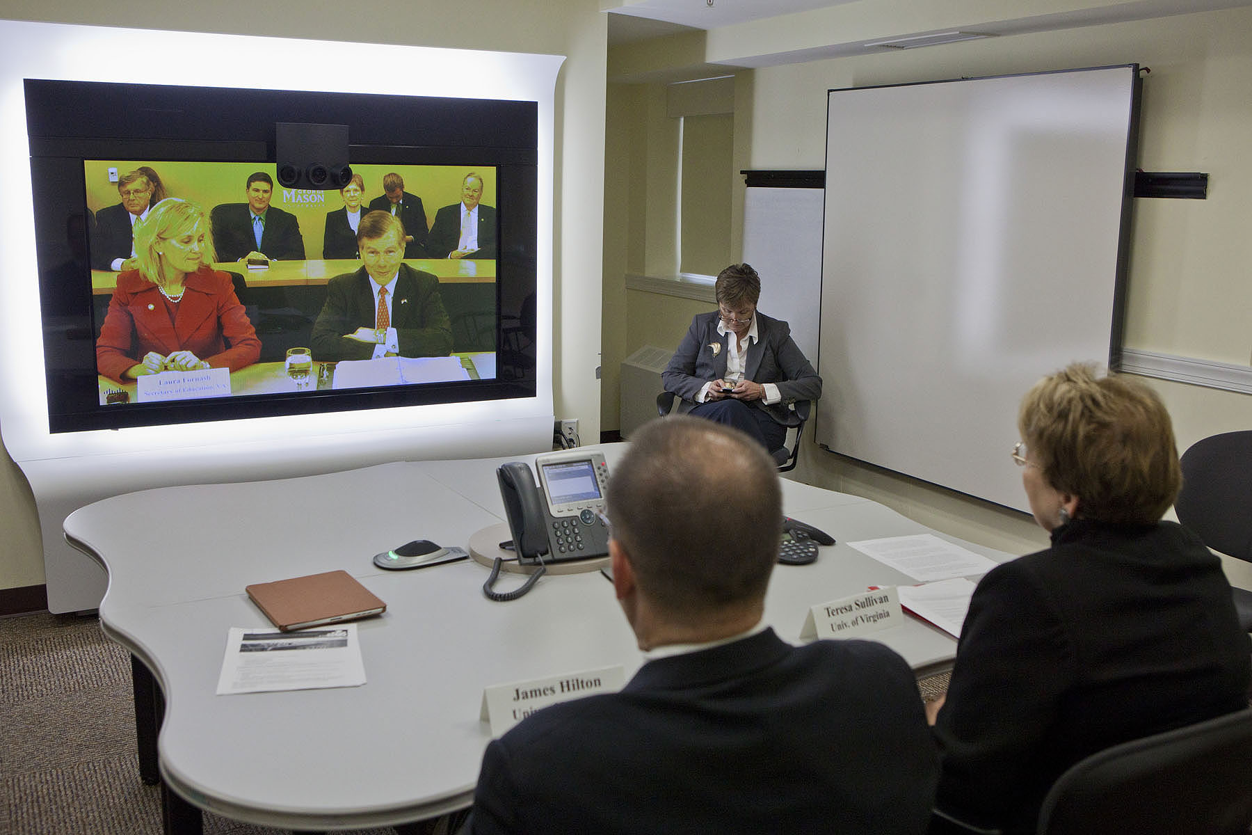Teresa Sullivan and James Hilton in a Tele Conference with others joining on a screen