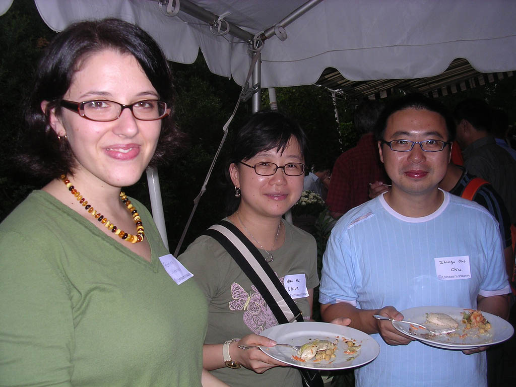 Students holding plates of food smiling at the camera