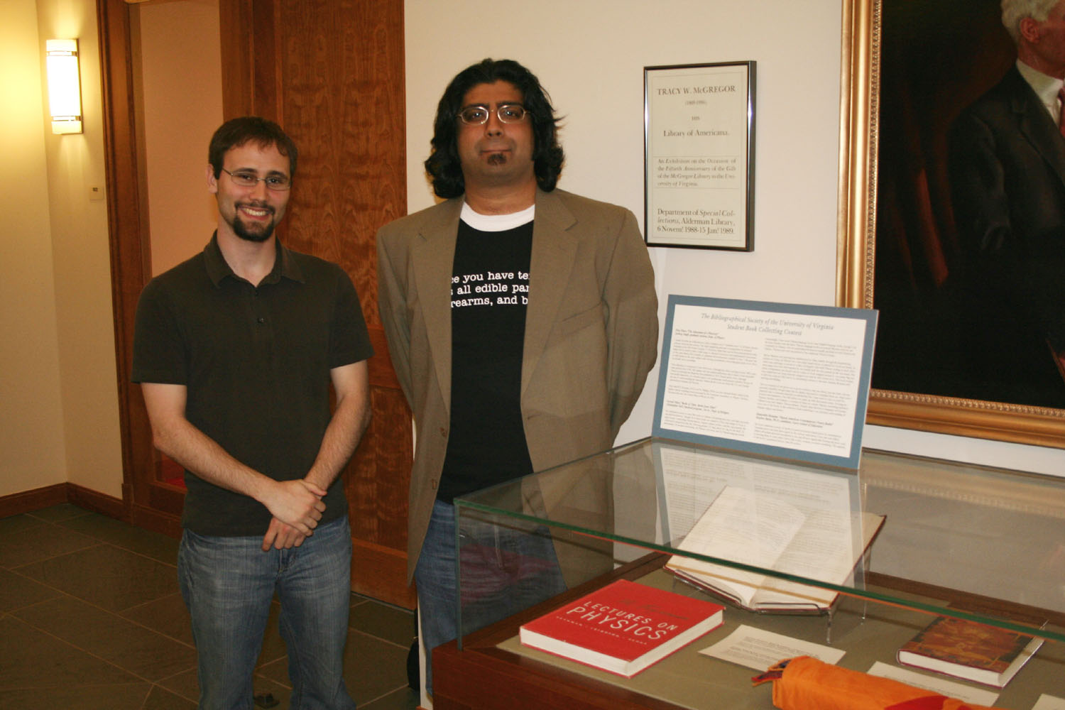Christopher Bell and Jaideep Singh stand next to a glass case full of books