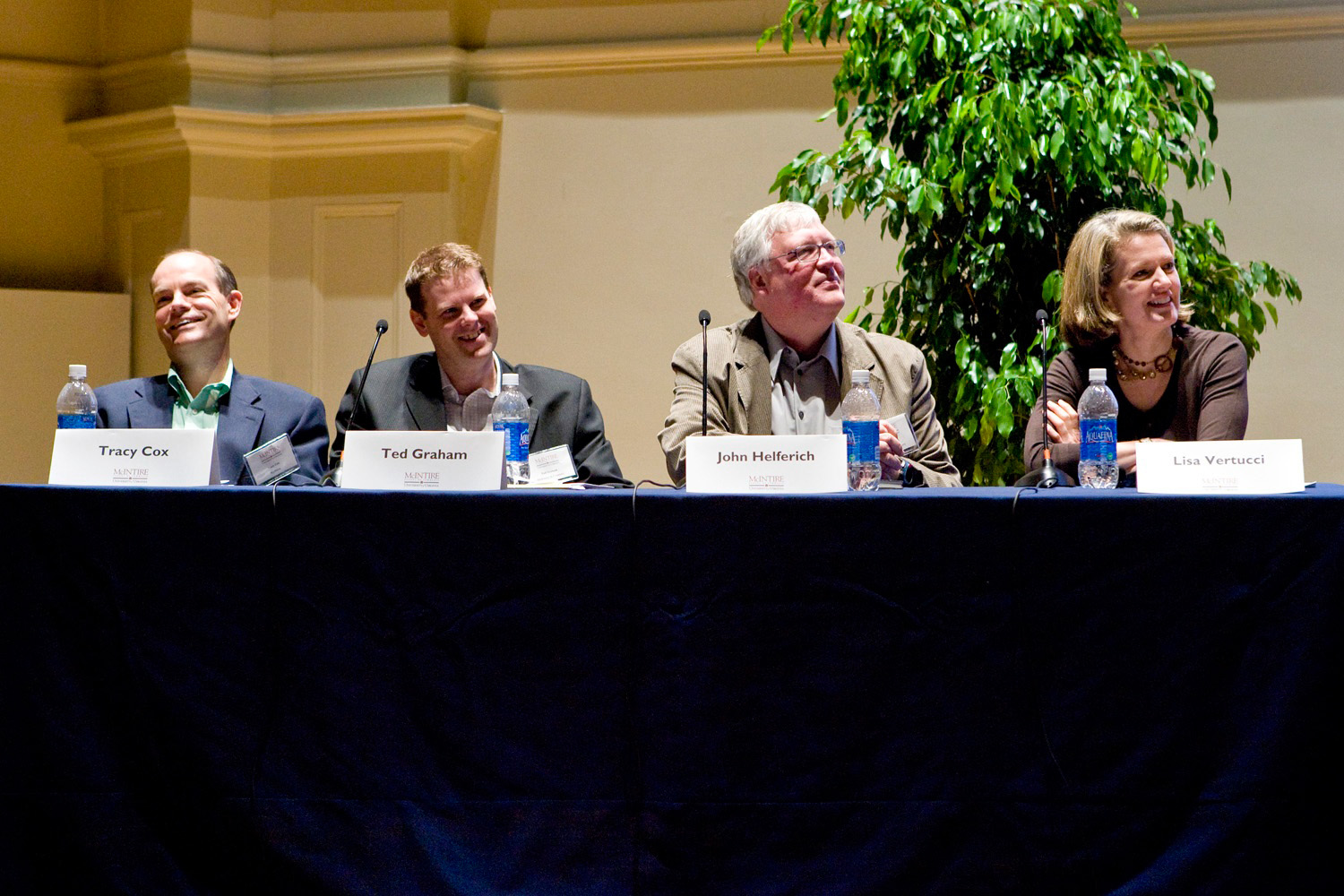 Panelists sitting at a table listening to  a question