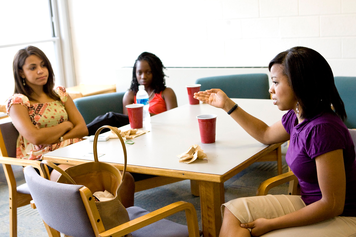 Three students sit at a table tlaking
