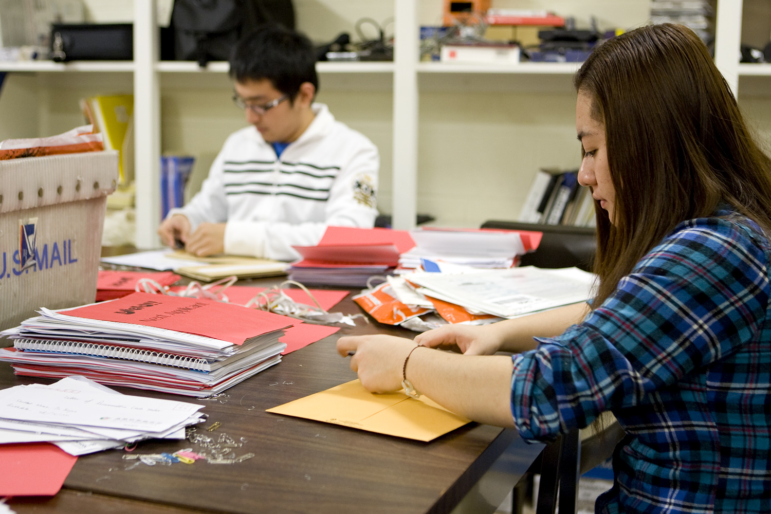 TingTing Jin (foreground) and Yujunjie Wu  working on packing letters to be mailed