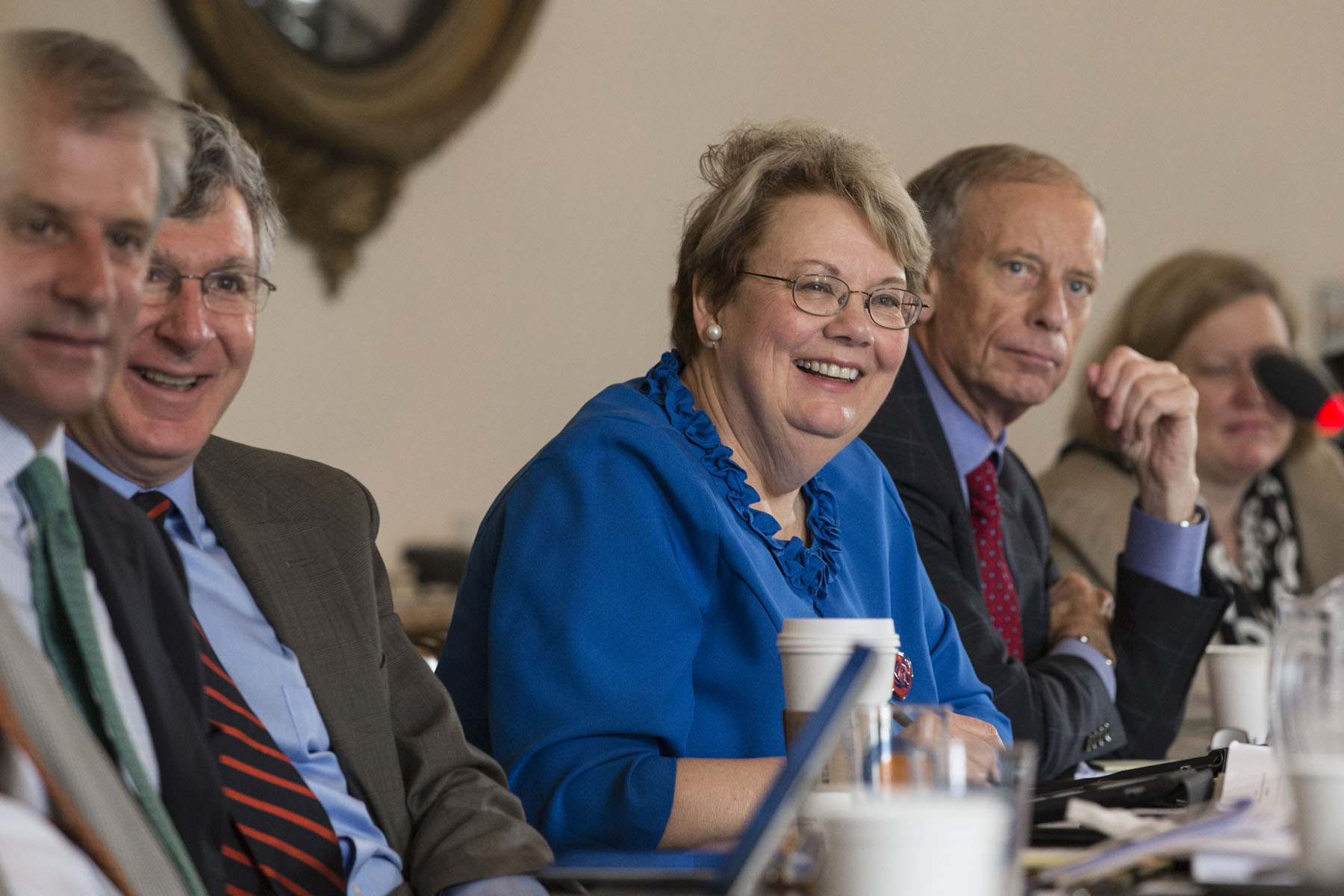 U.Va. President Teresa A. Sullivan sitting at a table with others listening to a speaker