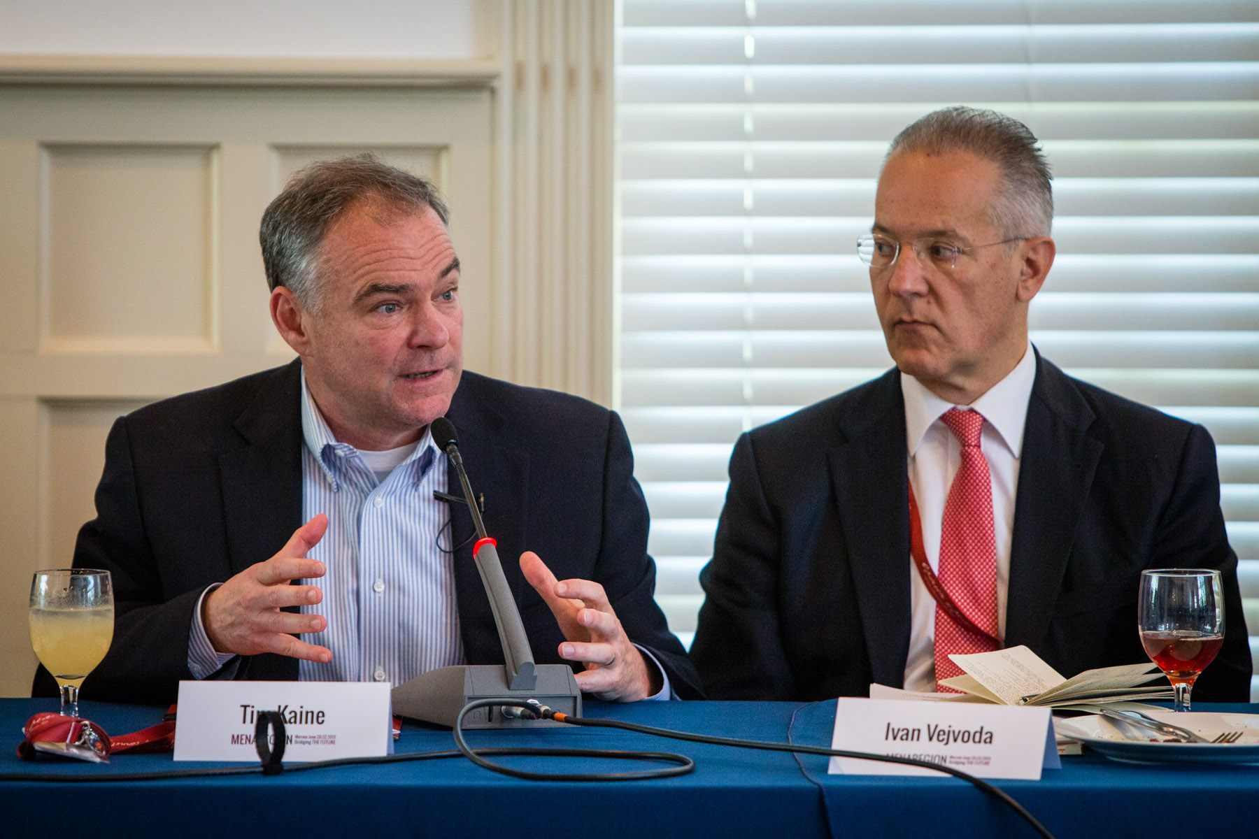Sen. Tim Kaine (left) speaks to an audience from a panelist table