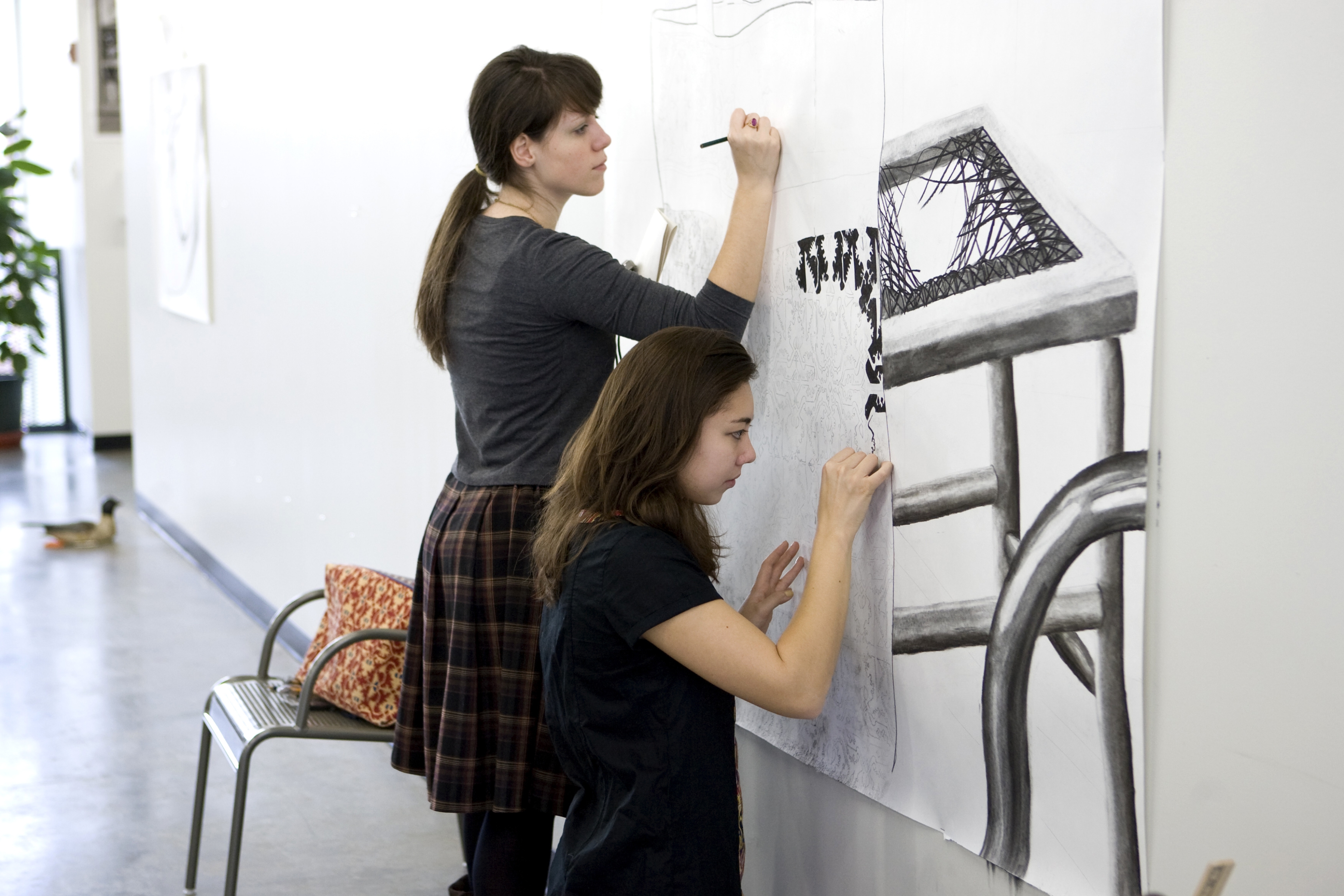 Two women sketching a mural