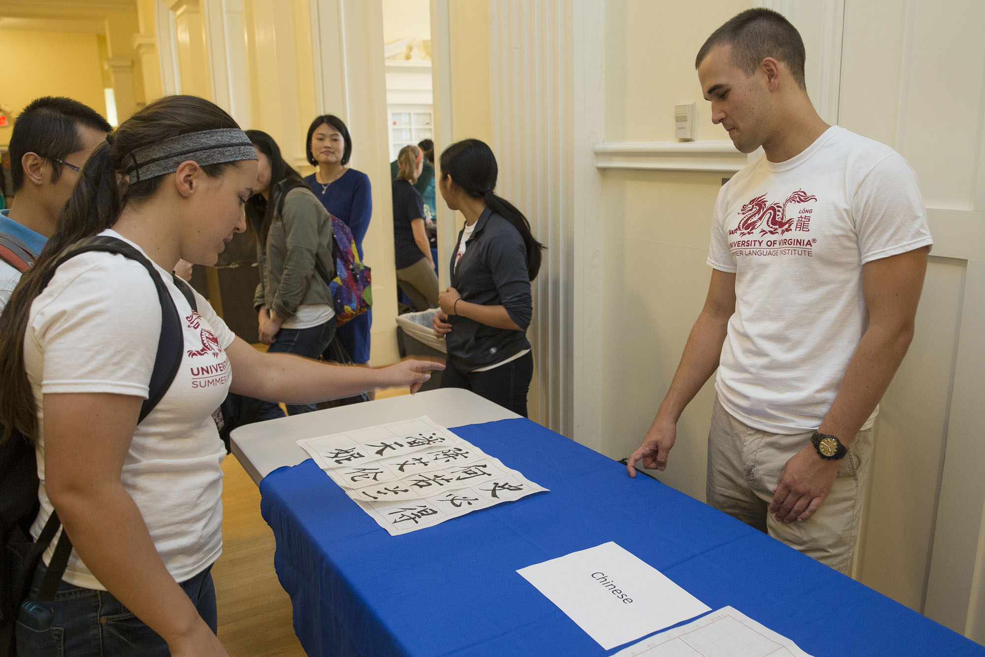 Air Force ROTC Cadet William Mullins (right), stands at a table with Chinese on it during a student fair