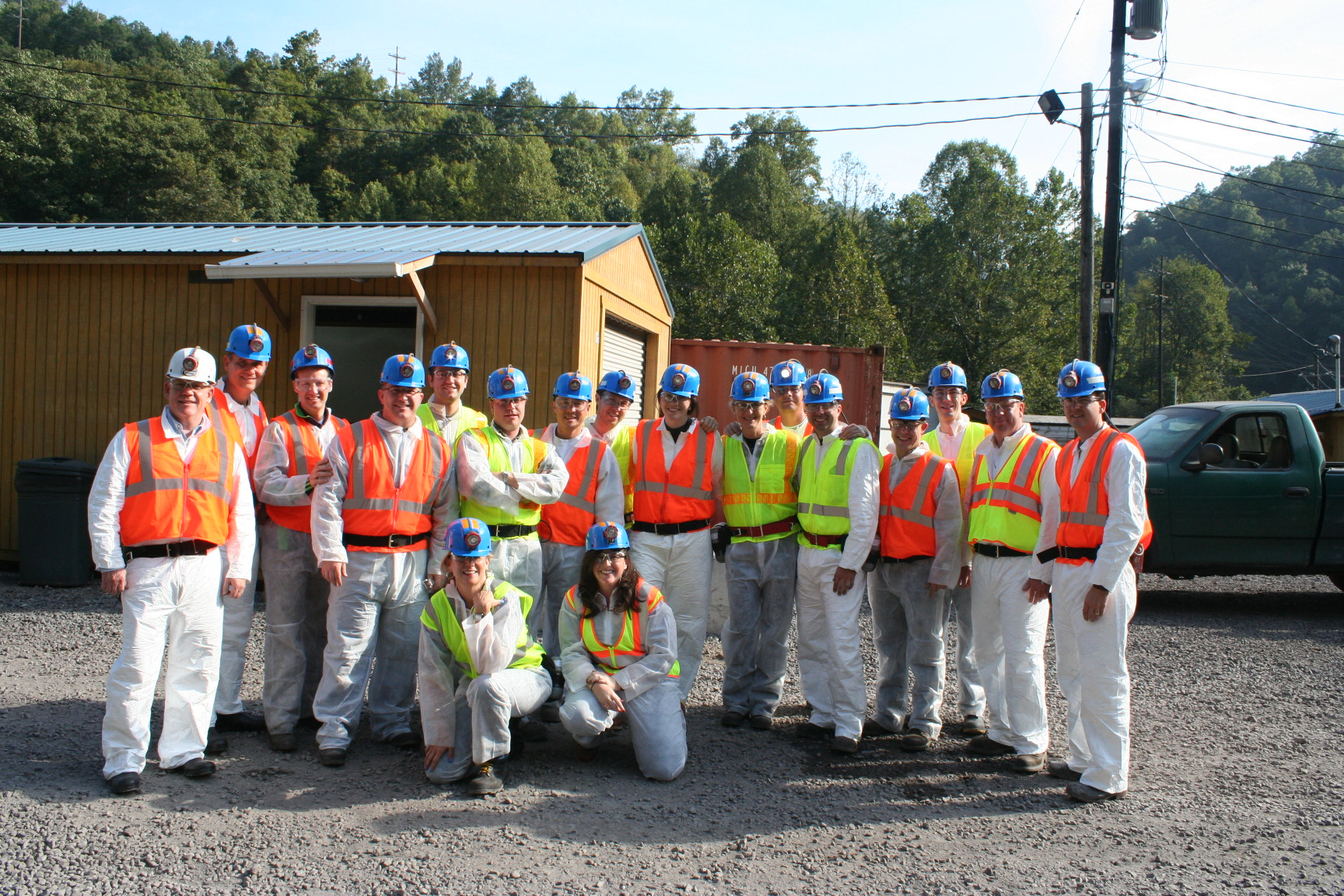 Group photo with everyone wearing coal miners hats and bright safety vests