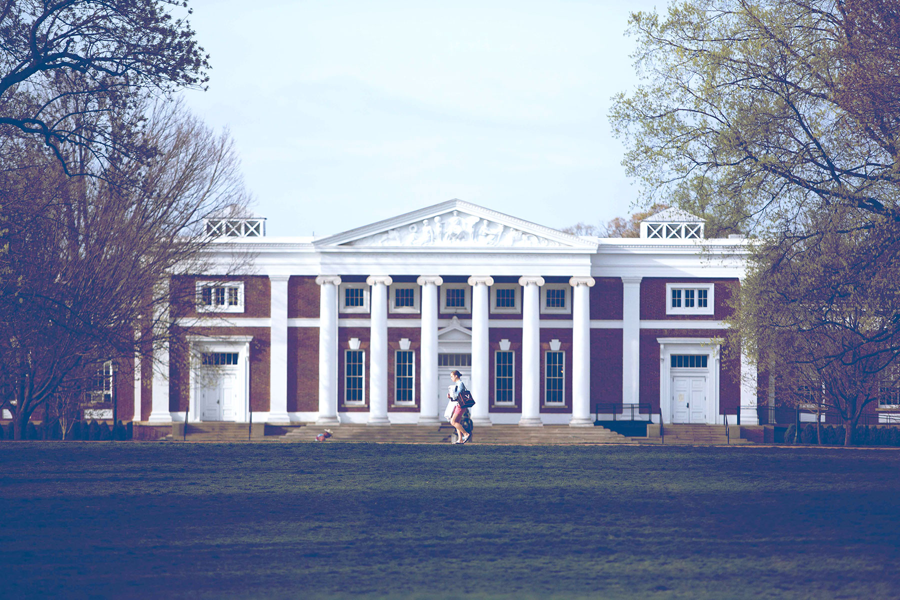Two people walking past a building on UVA's campus