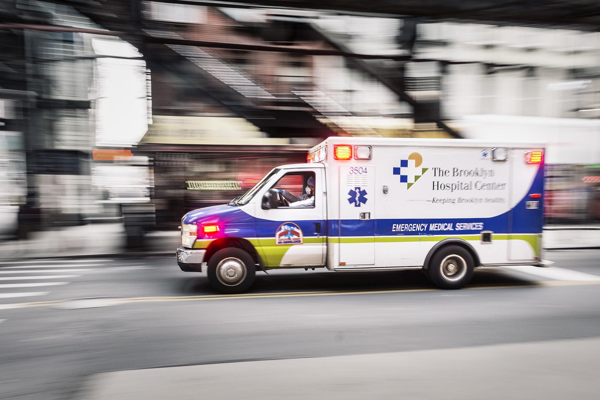 Blurred image of The Brooklyn Hospital Ambulance with lights on going down the road