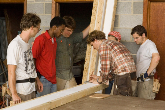 Students and faculty work together to put together a building frame