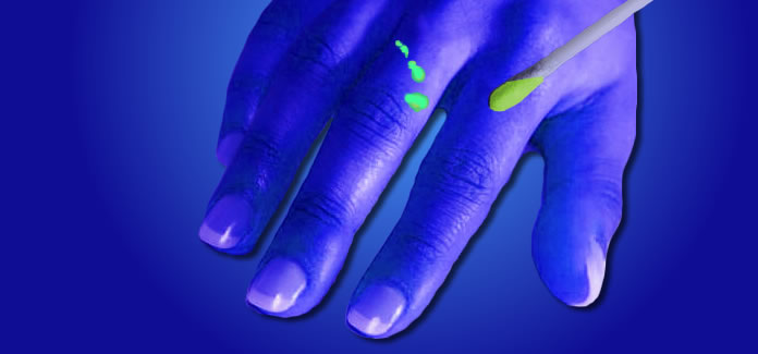 Blue hand with a green specs on a finger and on a q-tip
