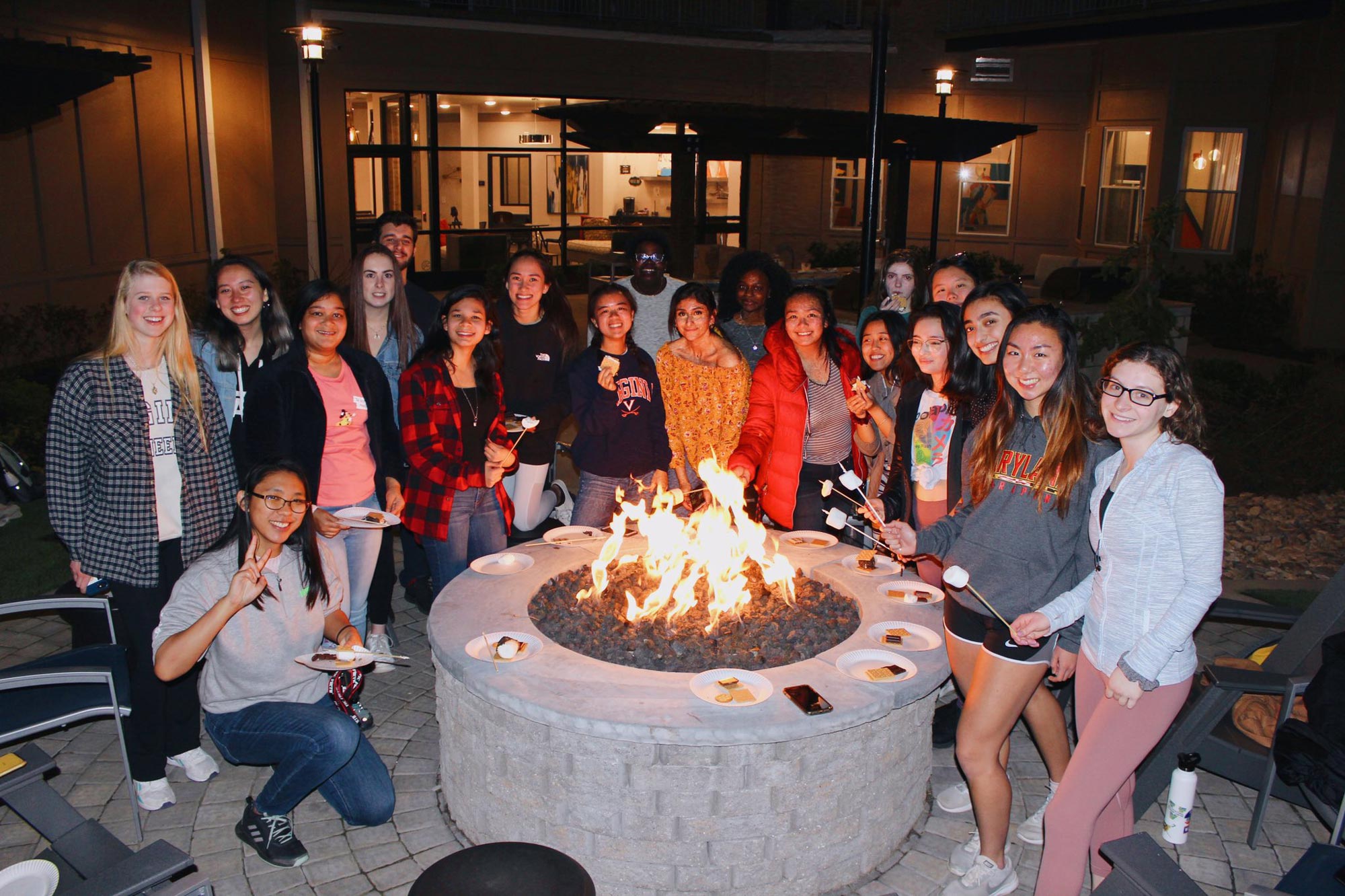 Girls Who Code participants surround a fire pit making smore's