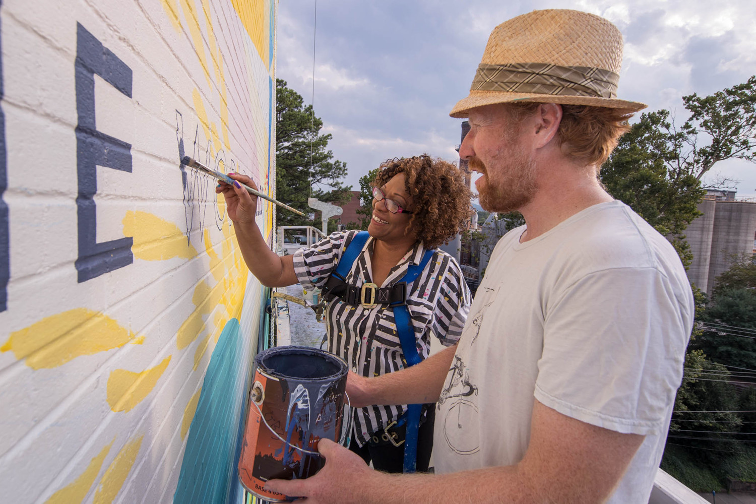 Muralist David Guinn and Rita Dove painting a mural on a building