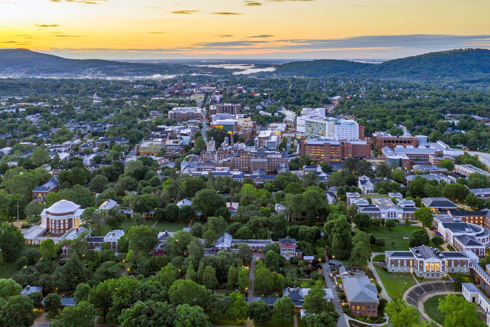 Arial View of the Rotunda and UVA health buildings as the sun sets creating a bright yellow sunset