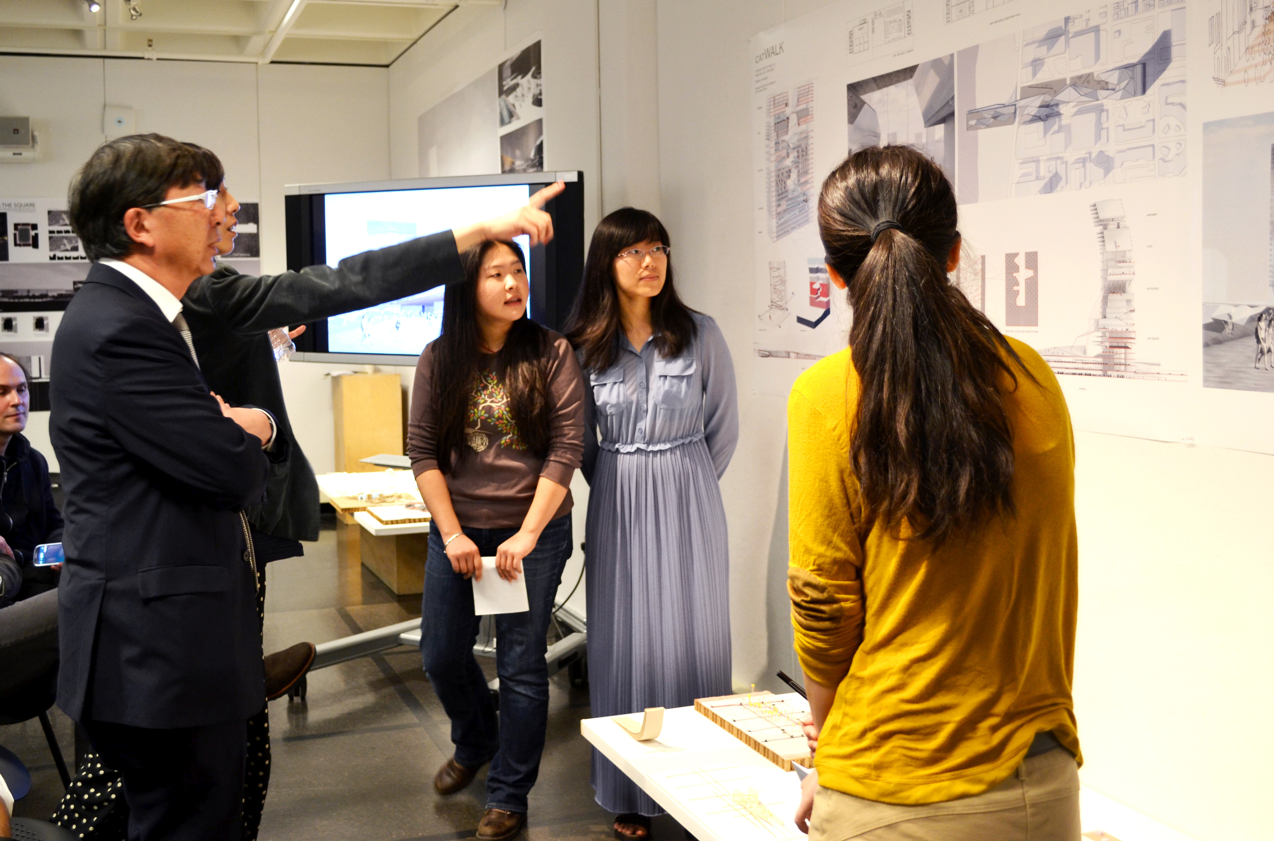 Toyo Ito talks to students about their designs hanging on the wall