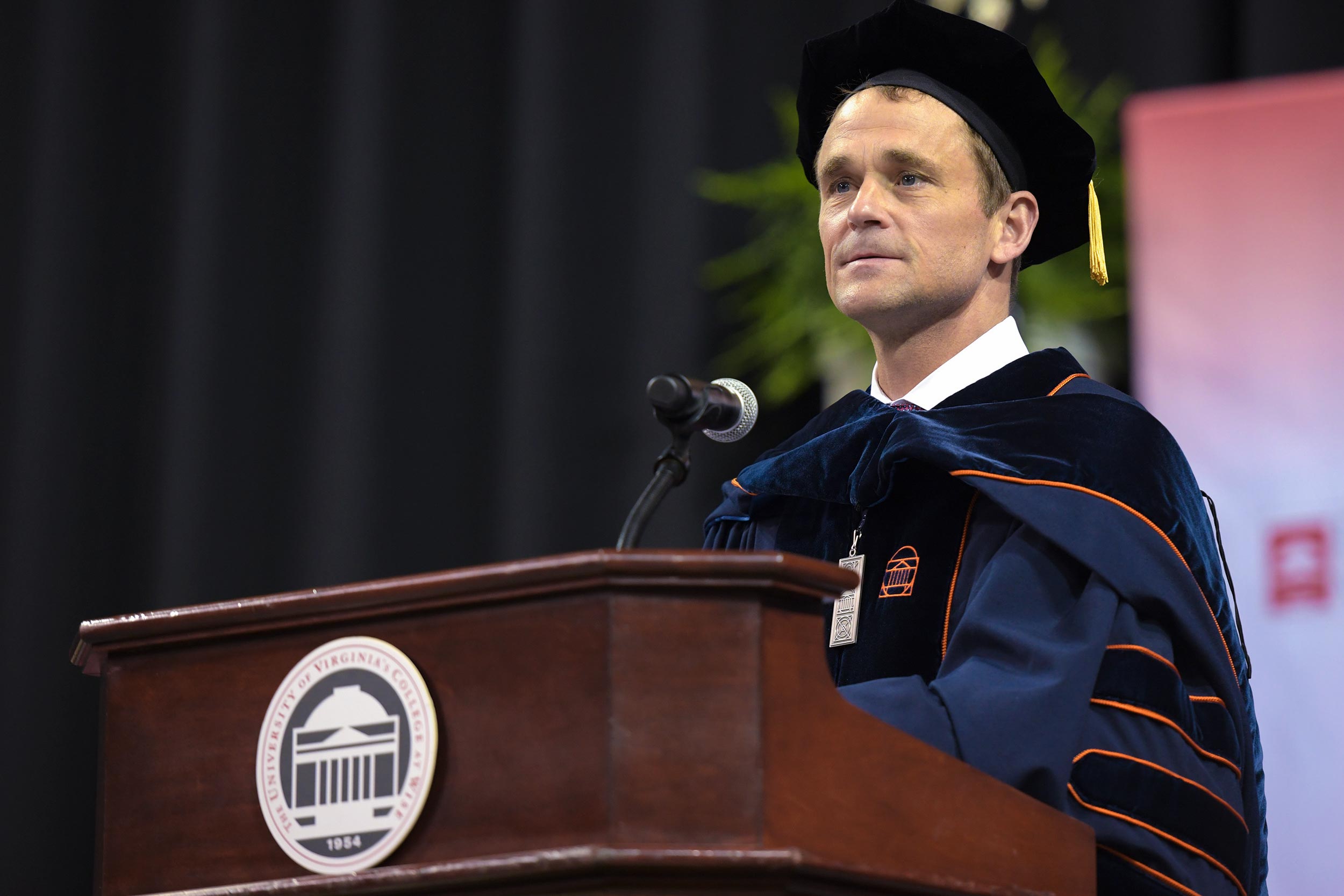 President Jim Ryan in graduation attire standing at a podium